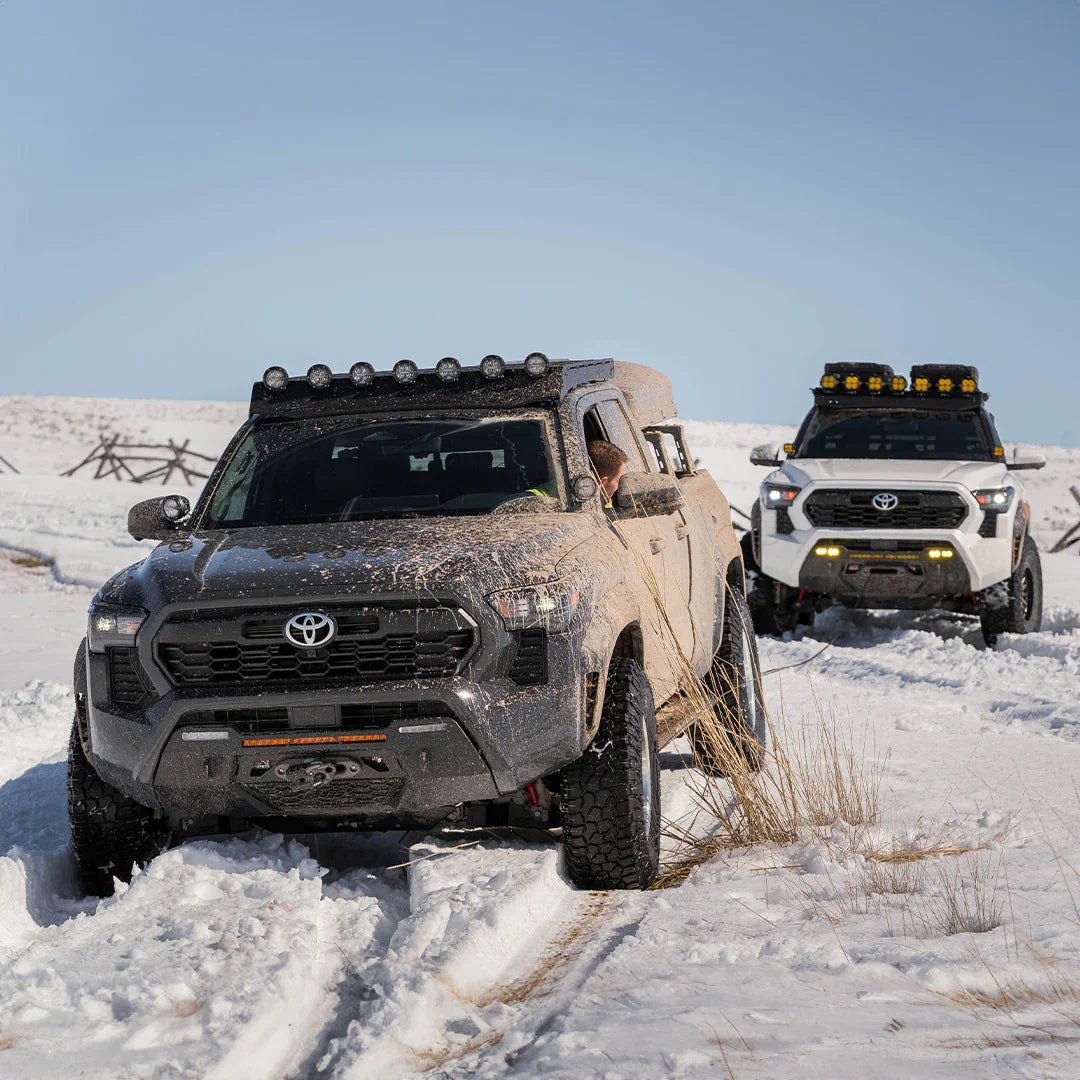 2024 Toyota Tacoma trucks off-roading in snow with overlanding accessories