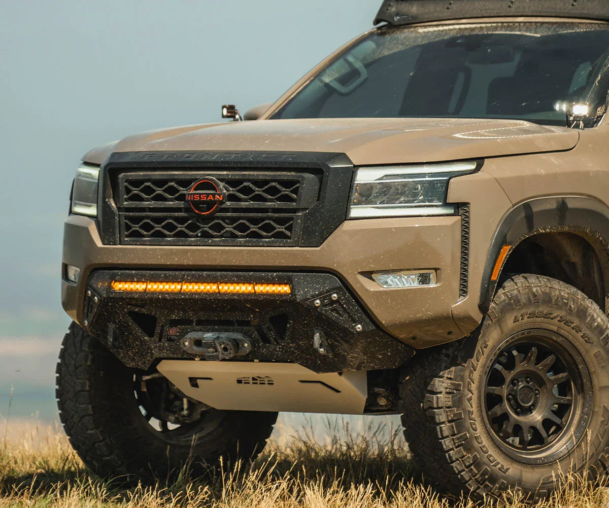 Off-road Nissan Frontier with rugged front bumper, LED light bar, and all-terrain tires outdoors