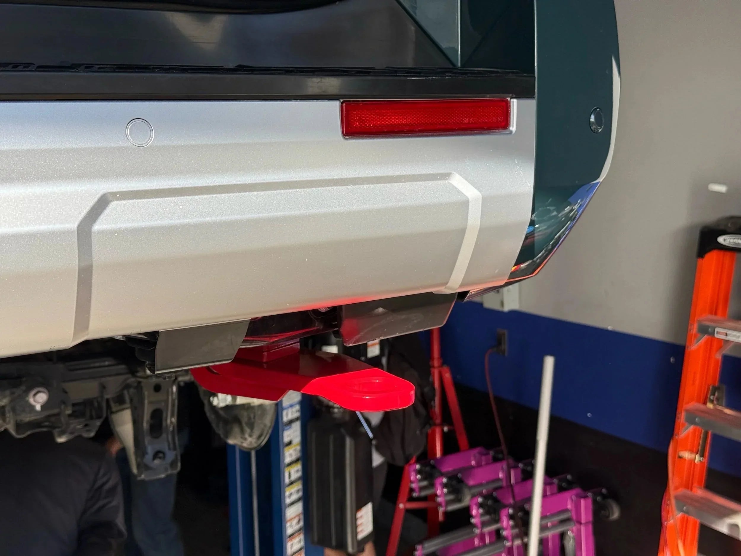 Rear bumper of off-road vehicle with red recovery point installed in garage setting