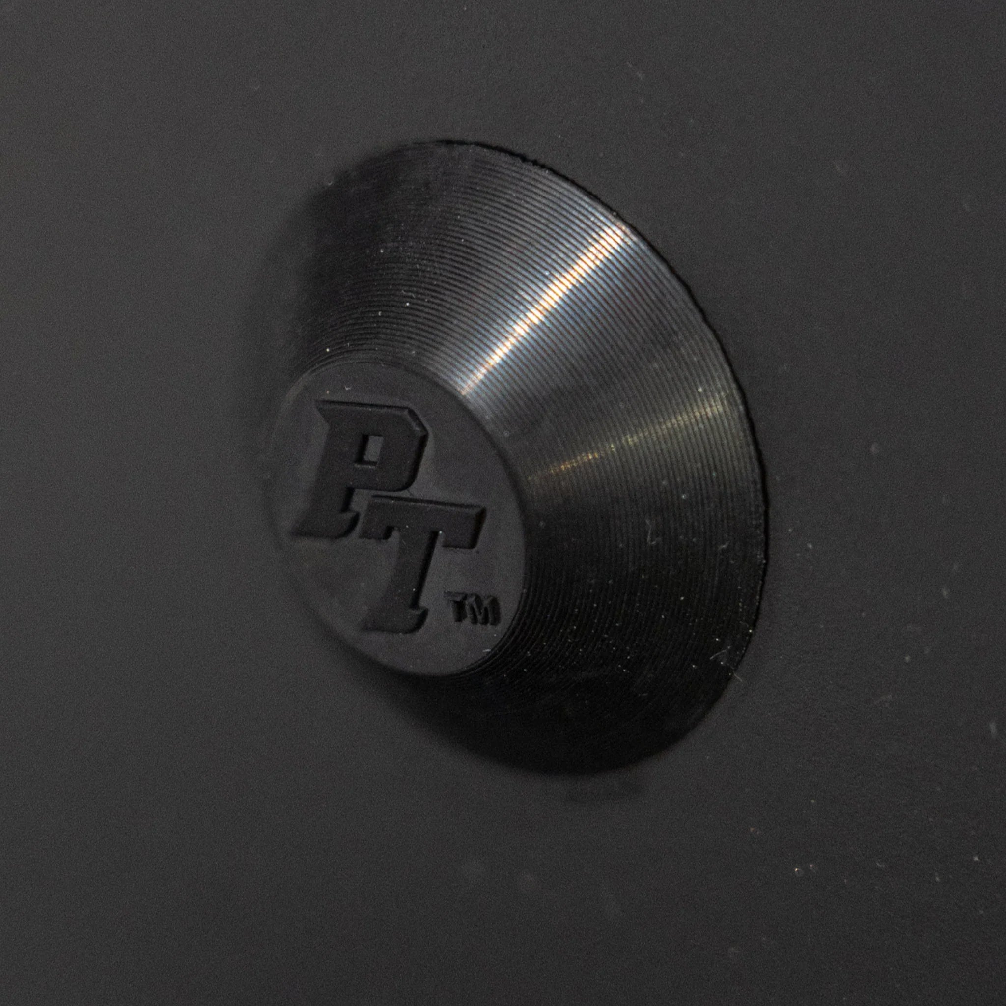 metal bumper cap with PT logo on matte black surface, close-up for overland vehicle