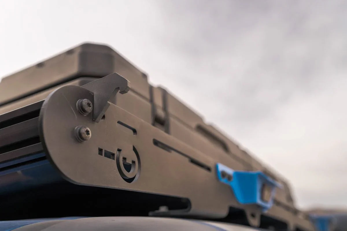 Close-up of a metal bottle opener mounted on a vehicle roof rack for overlanding gear