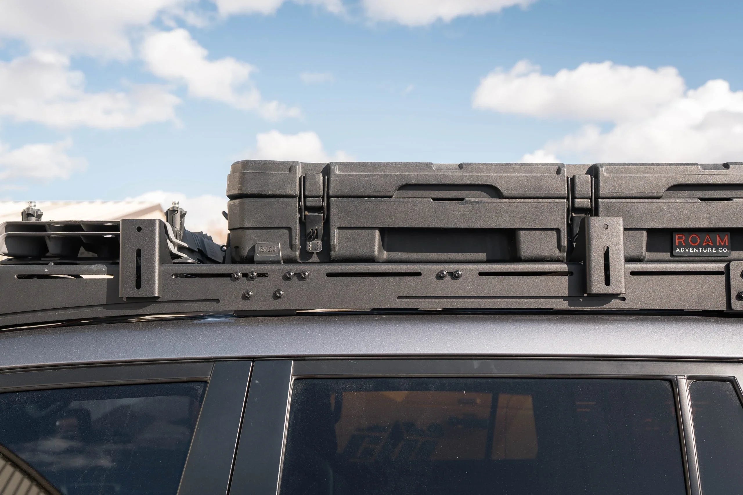 Heavy-duty roof rack awning mount with black storage case on SUV for overlanding