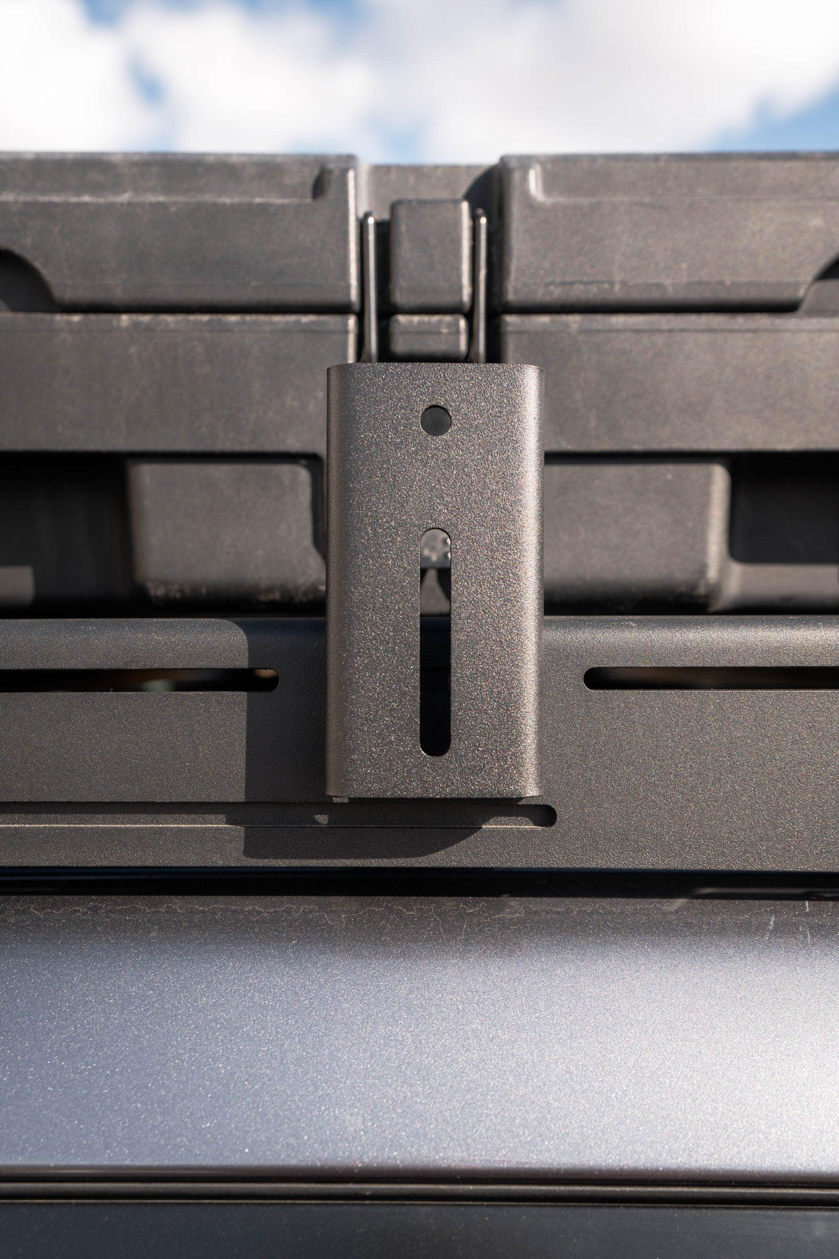 Steel awning mount bracket installed on a vehicle roof rack for overlanding gear