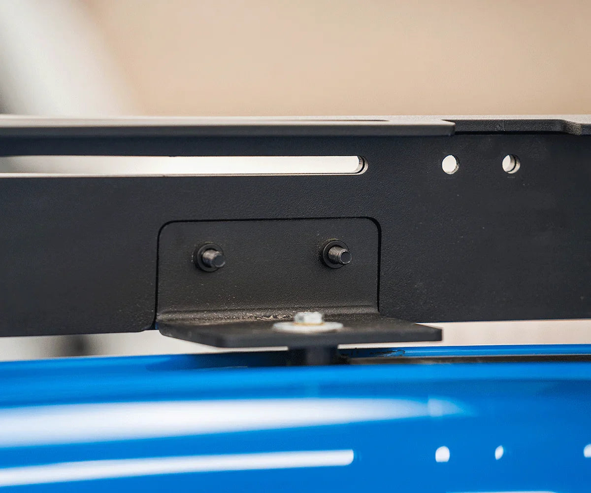 Close-up of black metal roof rack mounting bracket installed on blue vehicle
