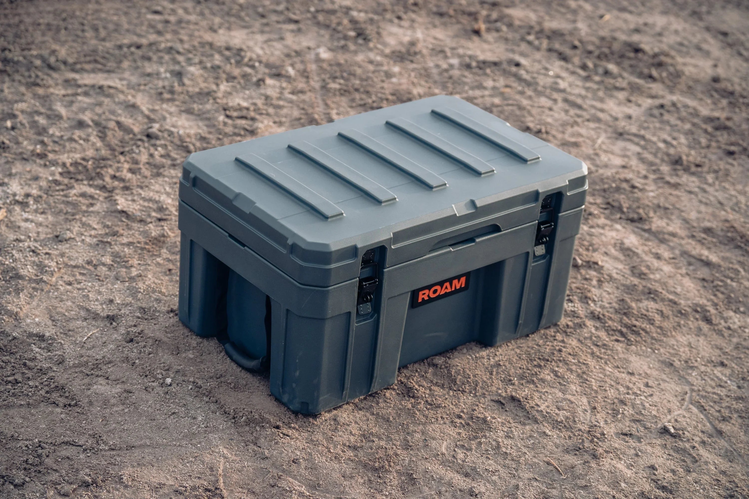 Heavy-duty grey ROAM storage box for overlanding and expedition gear on dirt ground