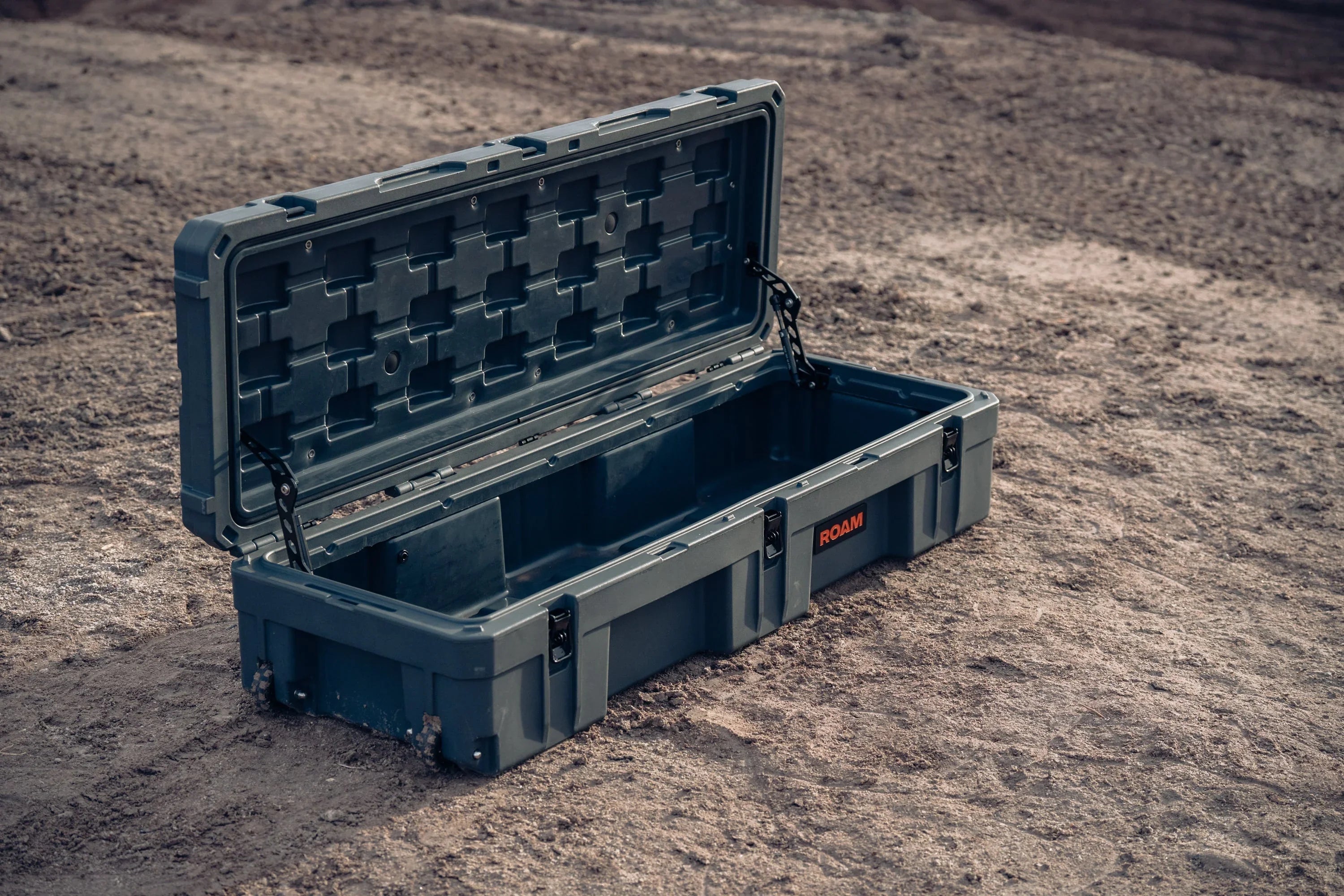 Heavy-duty open storage case for overlanding gear on rugged outdoor terrain.