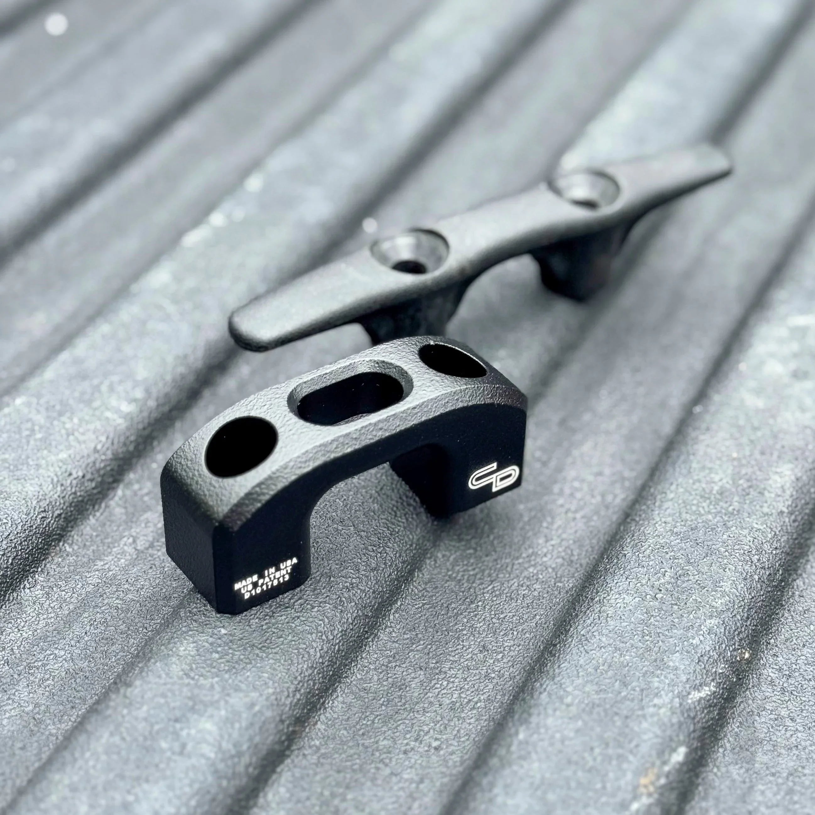 Black metal truck bed tie down cleats on a textured surface for off-road gear hauling