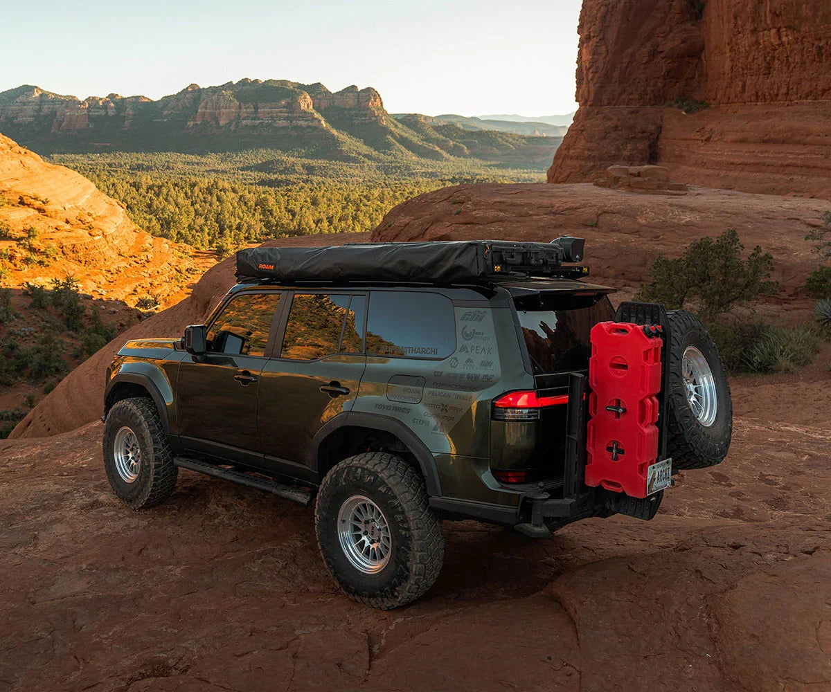 Off-road SUV with roof rack and jerry can on rocky terrain, adventure overlanding setup