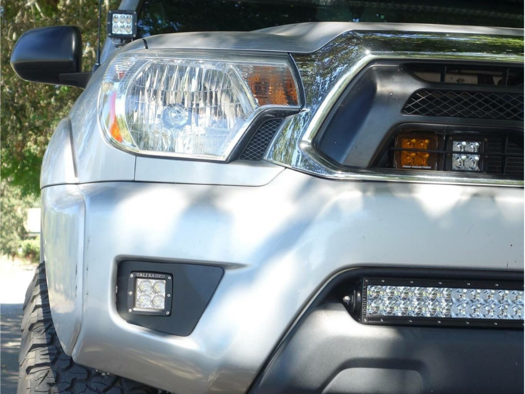 Close-up of Toyota truck front end with off-road LED lights and aftermarket accessories