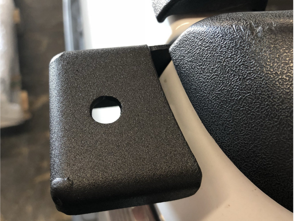 Close-up of a black metal mounting bracket on a textured vehicle accessory surface