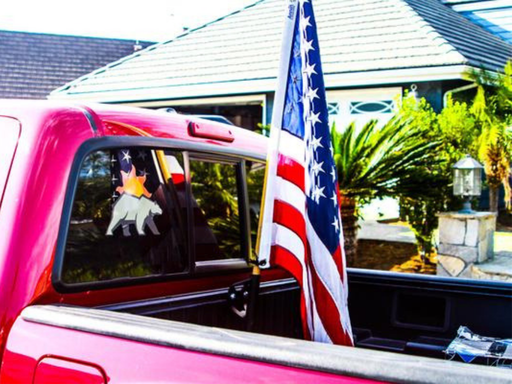 Red pickup truck with American flag and bear decal in suburban driveway