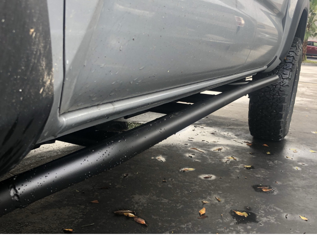Black steel rock sliders installed on a truck for off-road protection