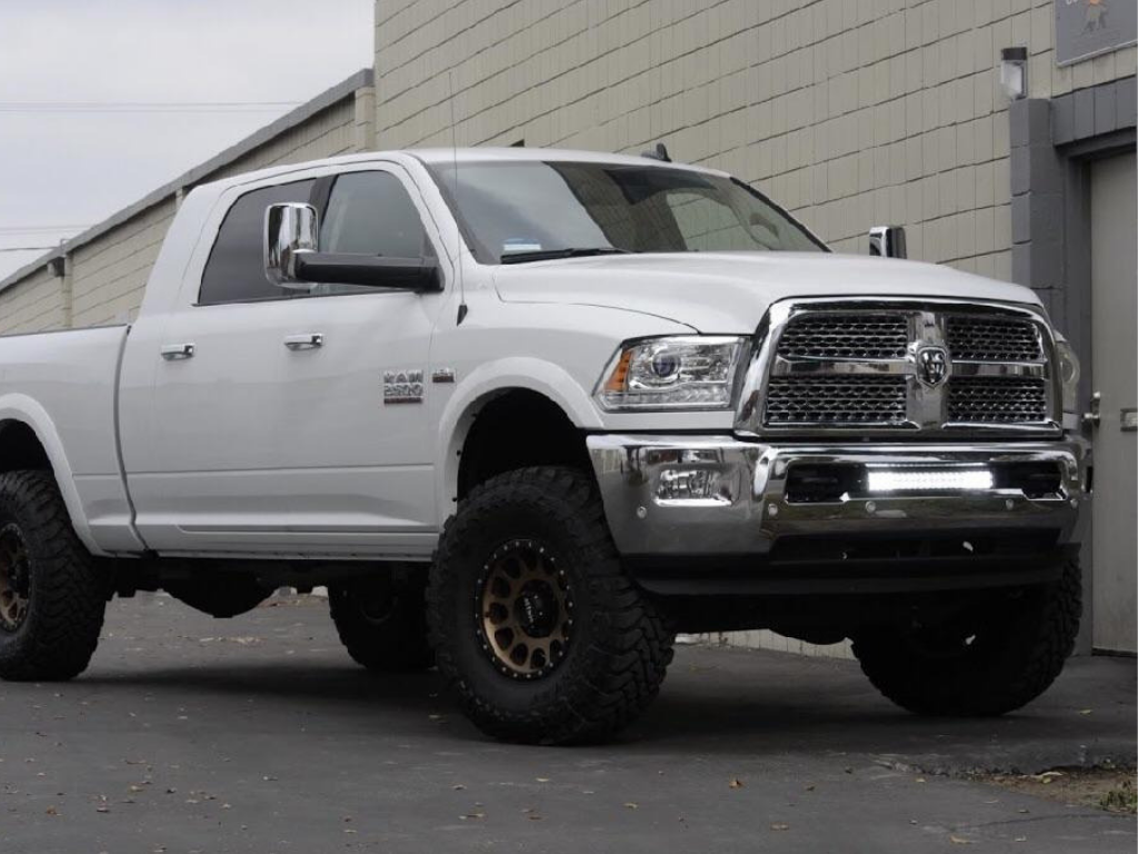 Lifted white RAM 2500 pickup with off-road tires and black wheels parked outdoors