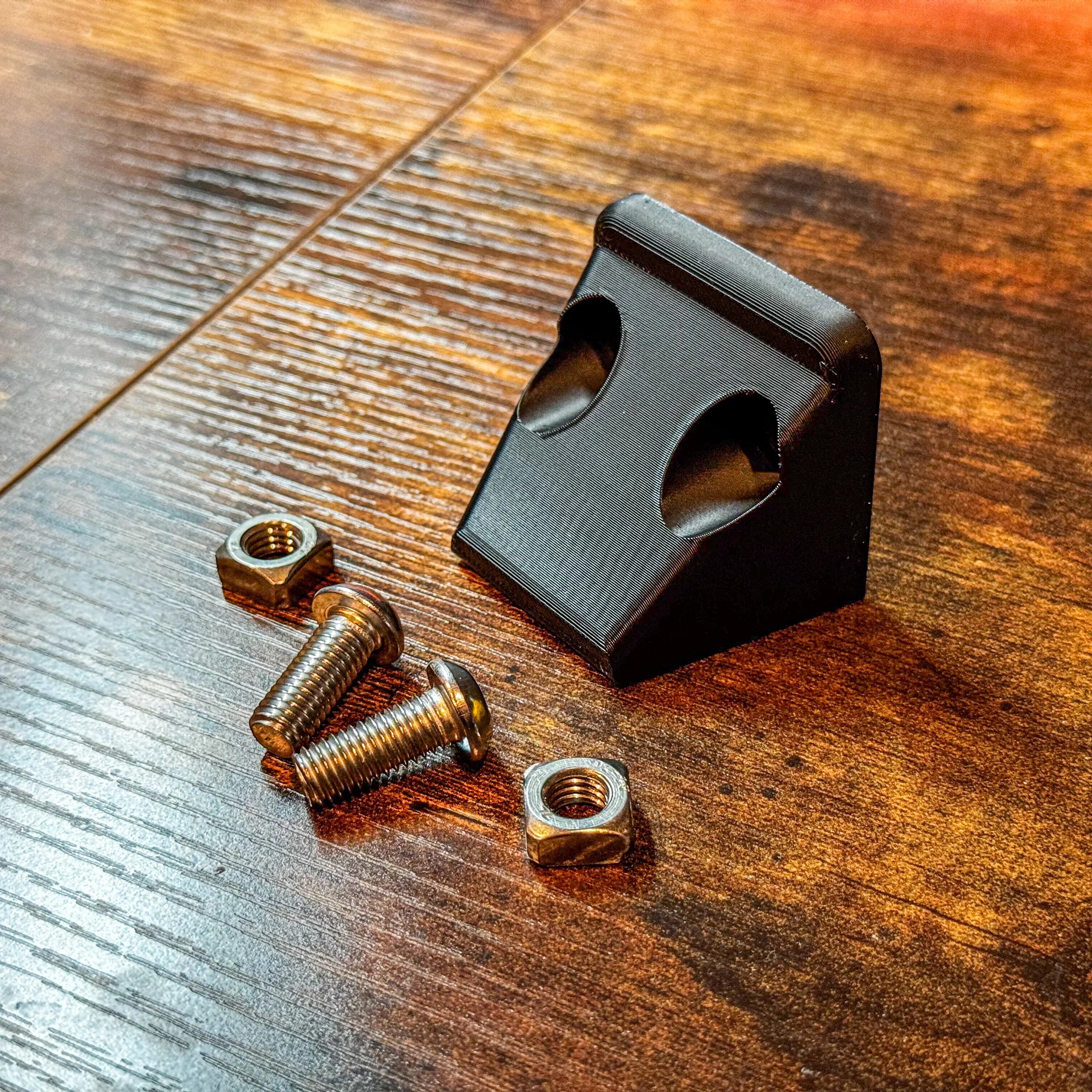 Black rear camera relocation mount with bolts and nuts for overlanding vehicles on wood surface