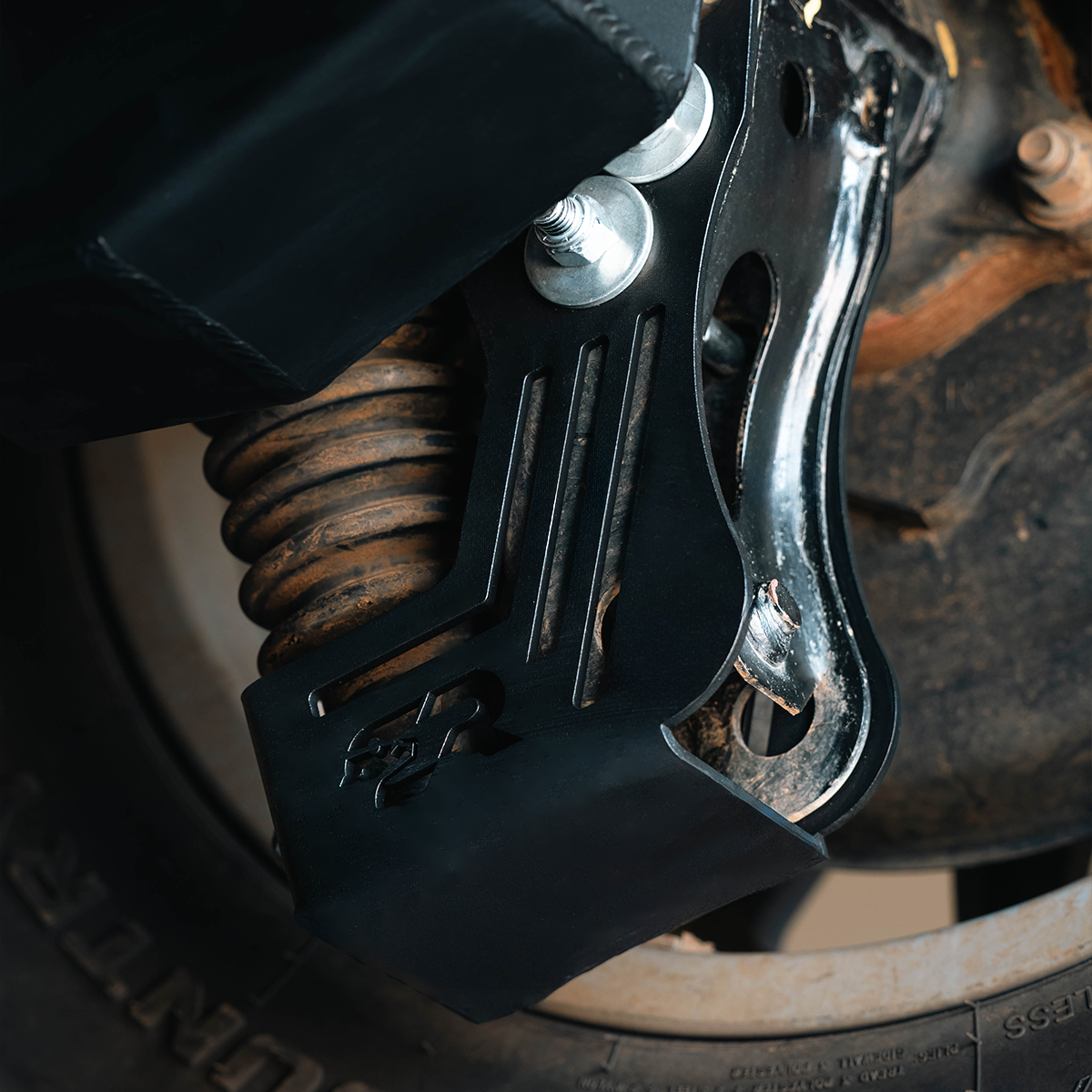 Rear shock skid plate installed on 2024 Toyota Tacoma suspension, close-up view