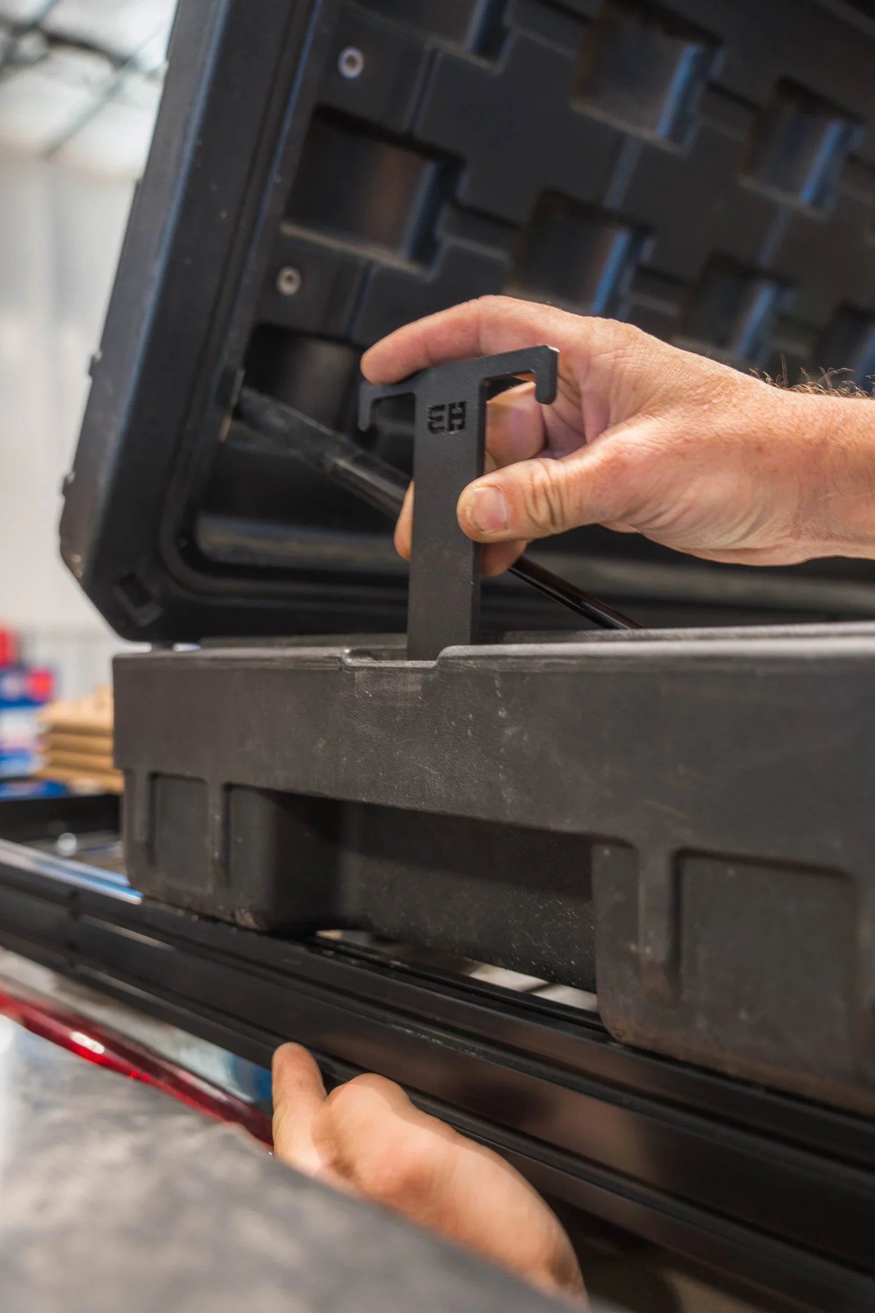 Hand installing rugged case mount bracket on overland vehicle storage box