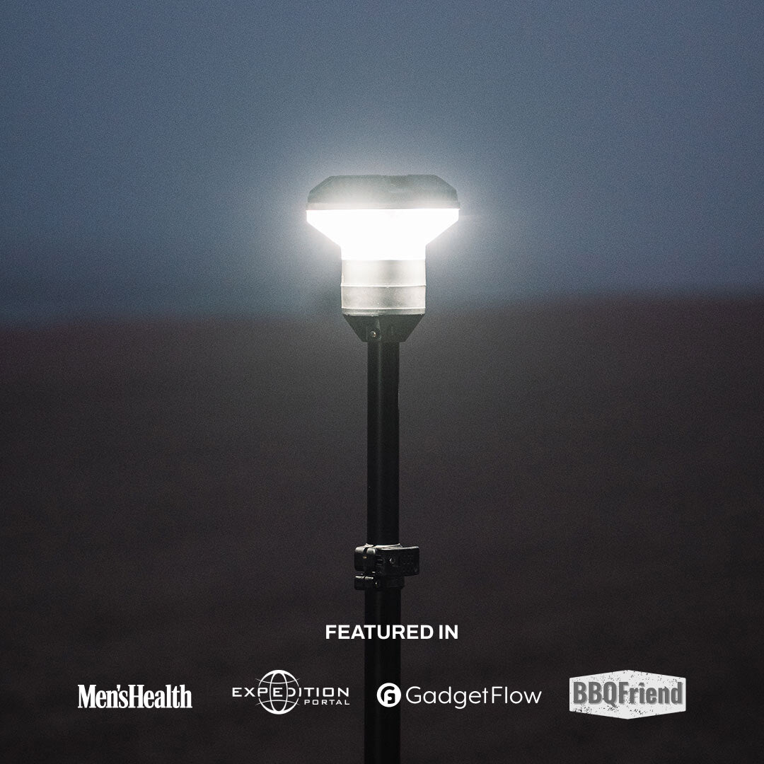 Portable LED camp light on pole outdoors at dusk, featured in major adventure magazines