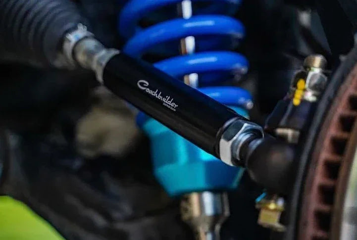 Close-up of off-road vehicle suspension with blue coil spring and adjustable control arm