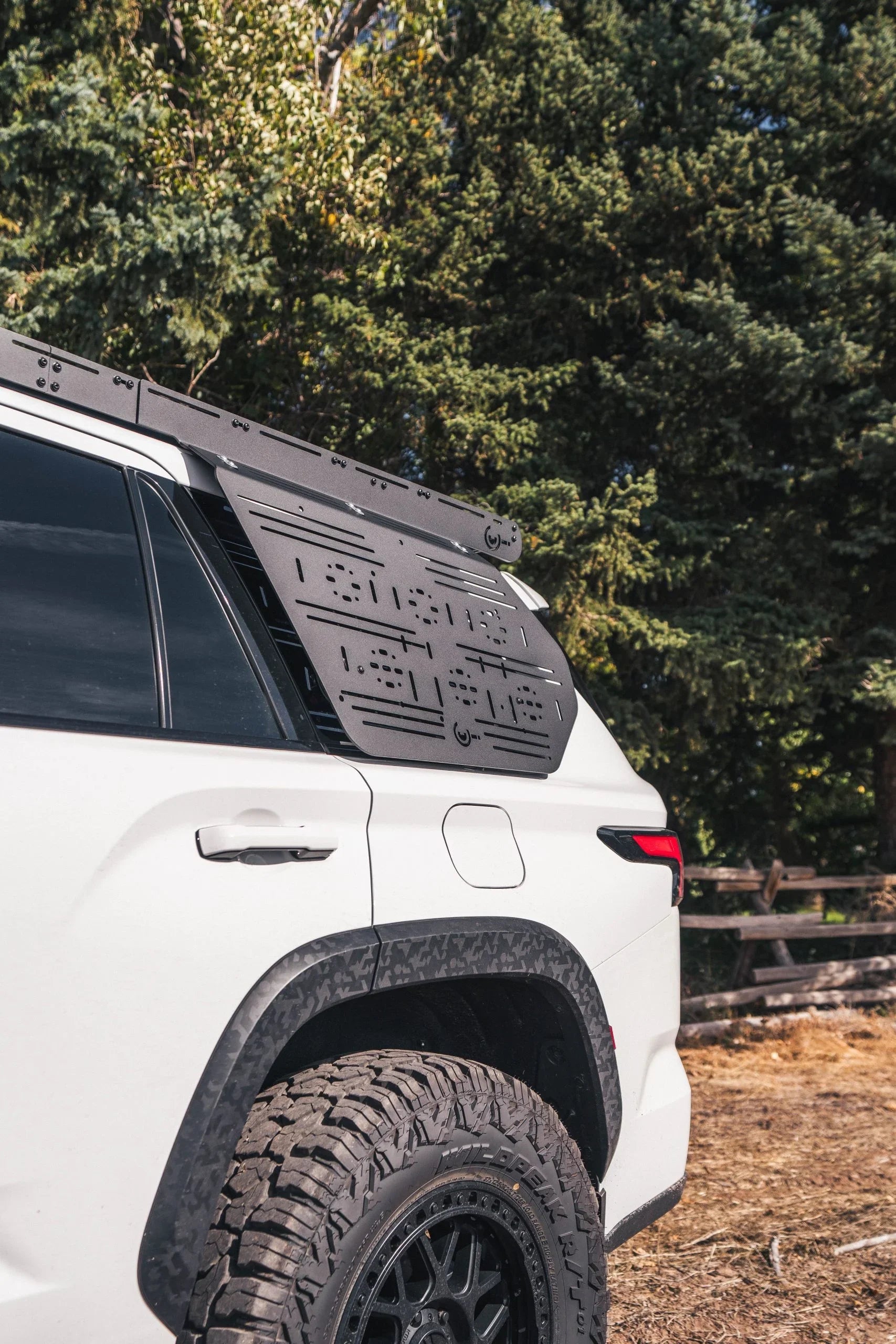 Toyota overland SUV with side panel molle rack and off-road tires in outdoor setting