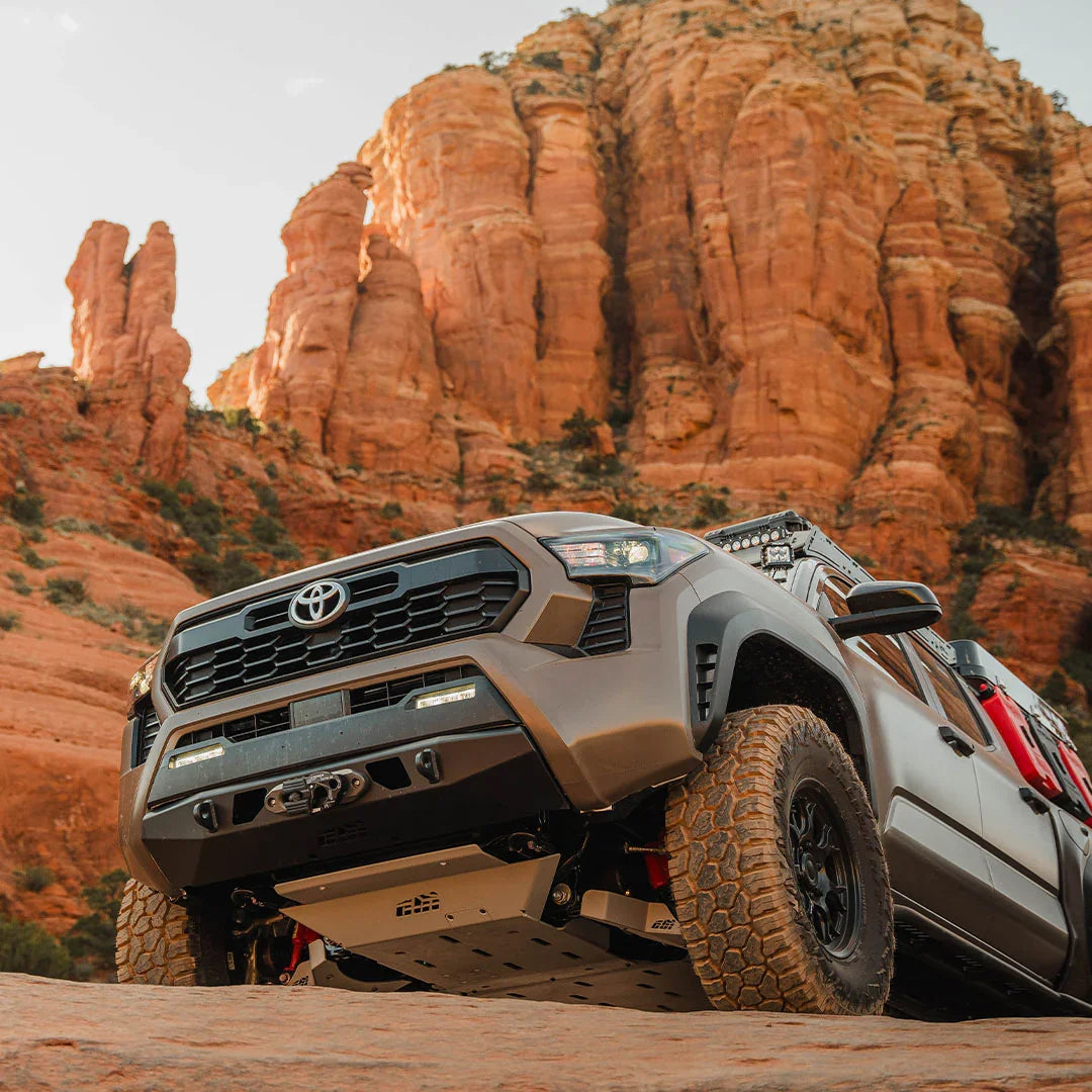 Lifted Toyota Tacoma with off-road accessories rock crawling in red sandstone canyon