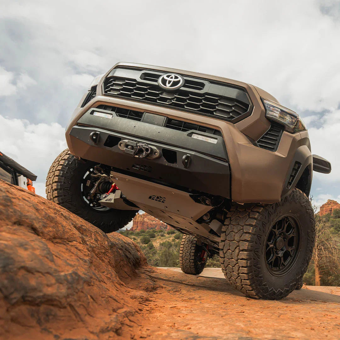 Toyota Tacoma off-road truck climbing rocky terrain with aftermarket skid plate and rugged tires
