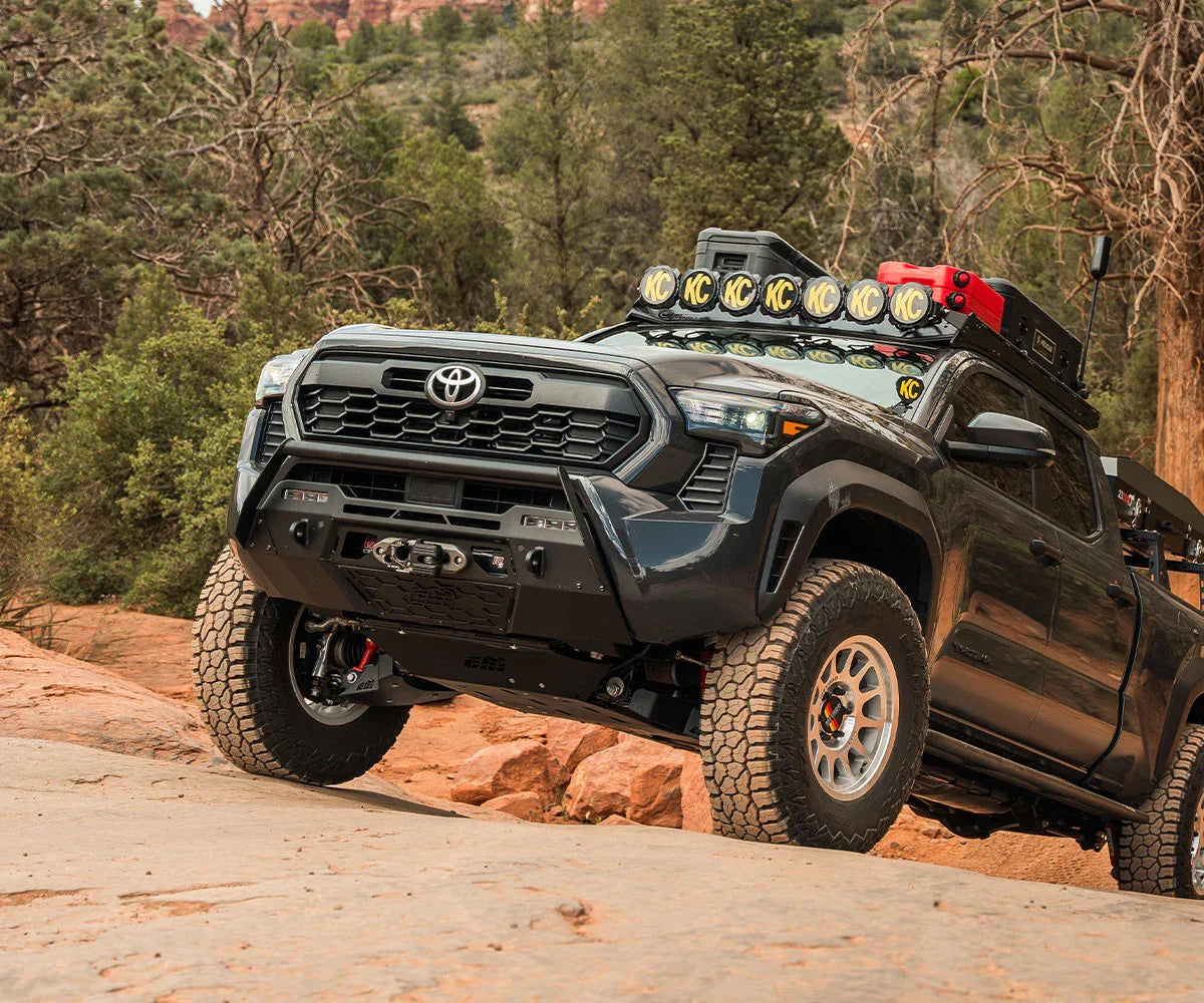 Toyota Tacoma outfitted with off-road accessories and roof lights on rugged trail