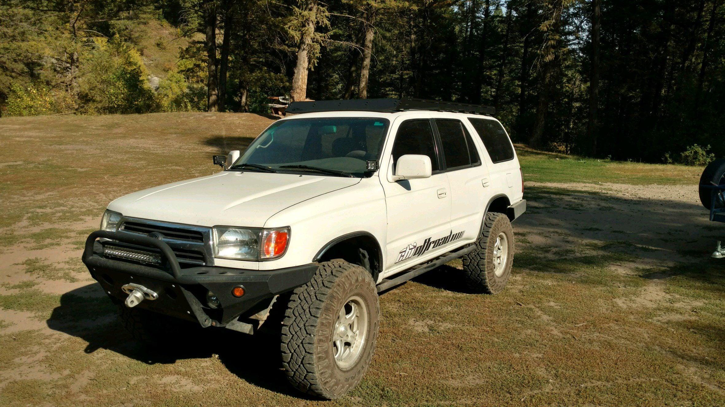 White Toyota 4Runner with roof rack and off-road bumper parked outdoors