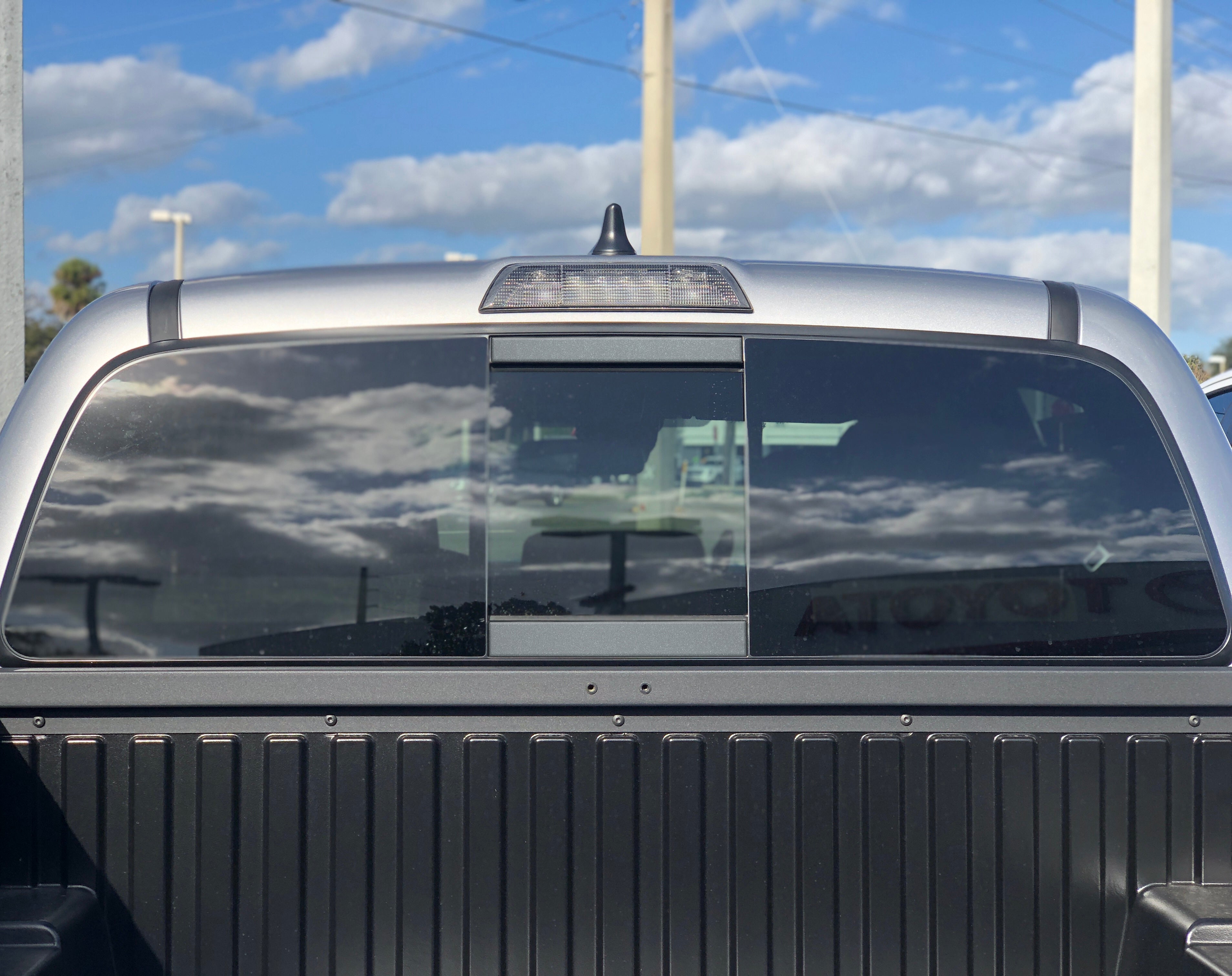 Toyota Tacoma rear sliding window with privacy glass and third brake light, outdoor view