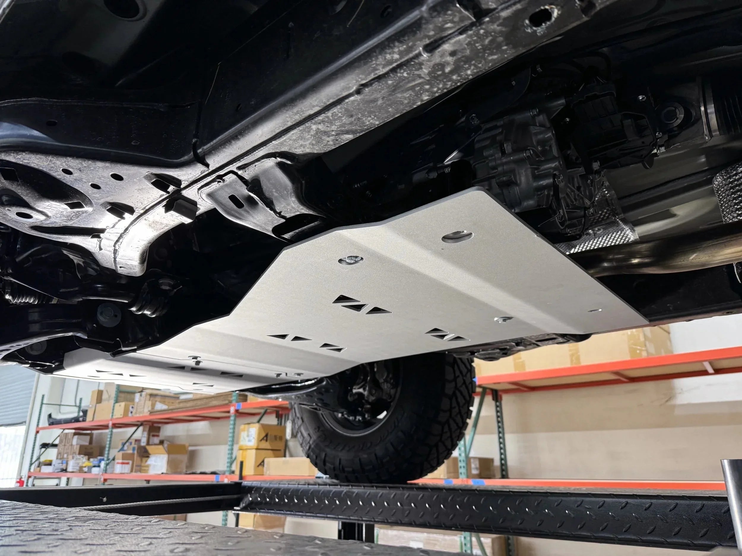 Aluminum skid plate installed under off-road vehicle, protecting underside components.