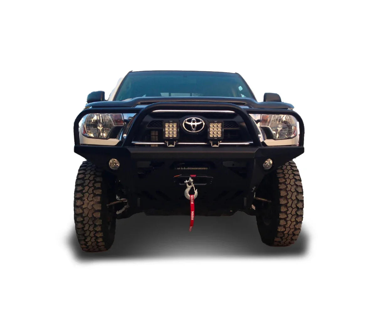 Front view of a Toyota Tacoma with off-road bumper, winch, LED lights, and rugged tires