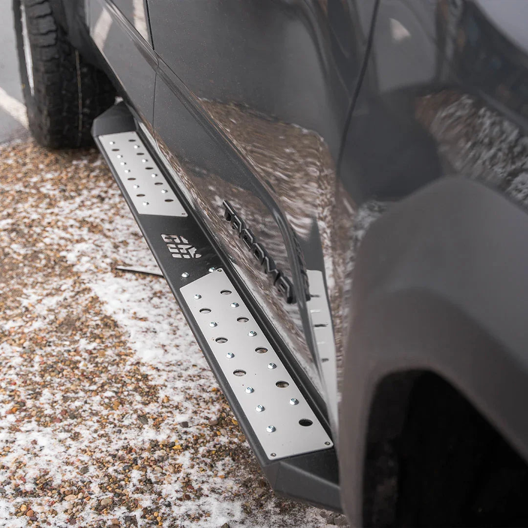 Toyota Tacoma side steps with rugged metal plates on snowy pavement