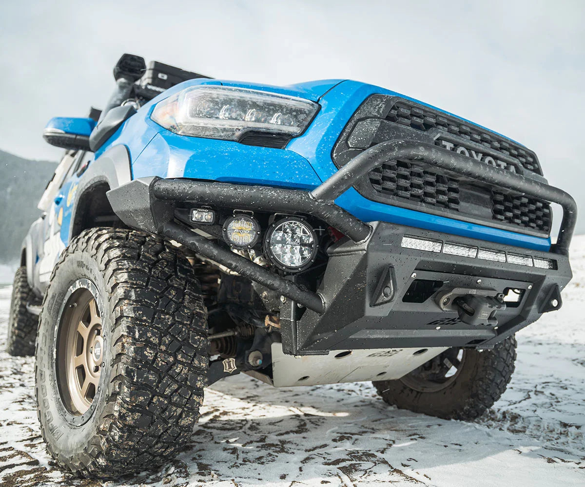 Blue Toyota Tacoma TRD Pro overland build with off-road bumper and rugged tires in snow