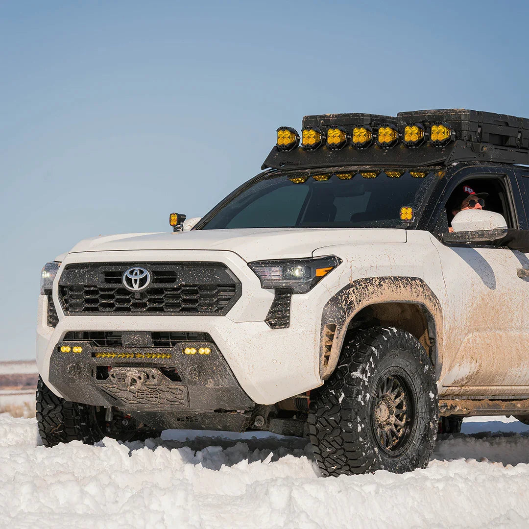Toyota Tacoma 4th Gen off-road in snow with aftermarket lights and rugged tires