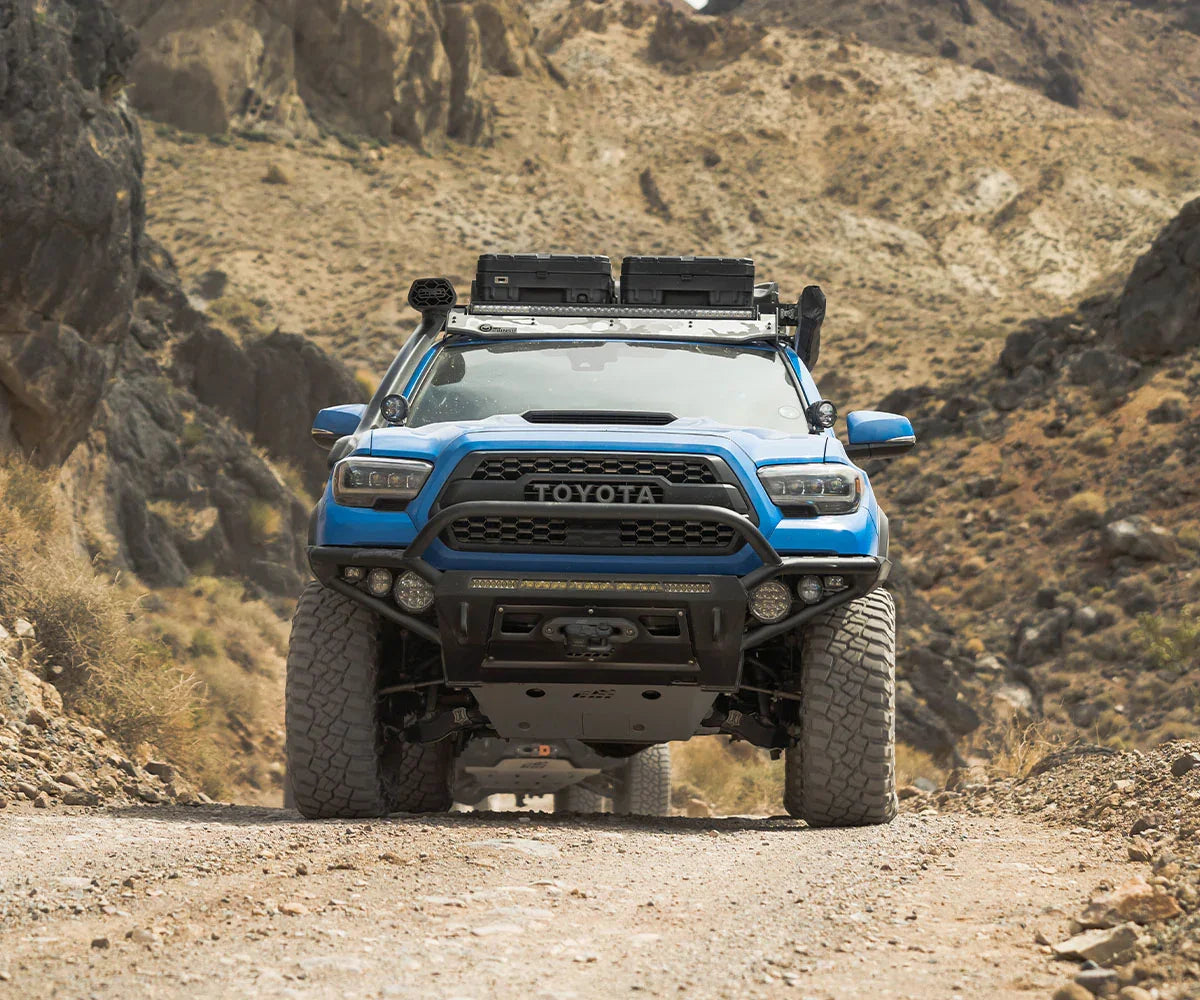 Blue Toyota Tacoma with Dakar hybrid front bumper on a rocky off-road trail