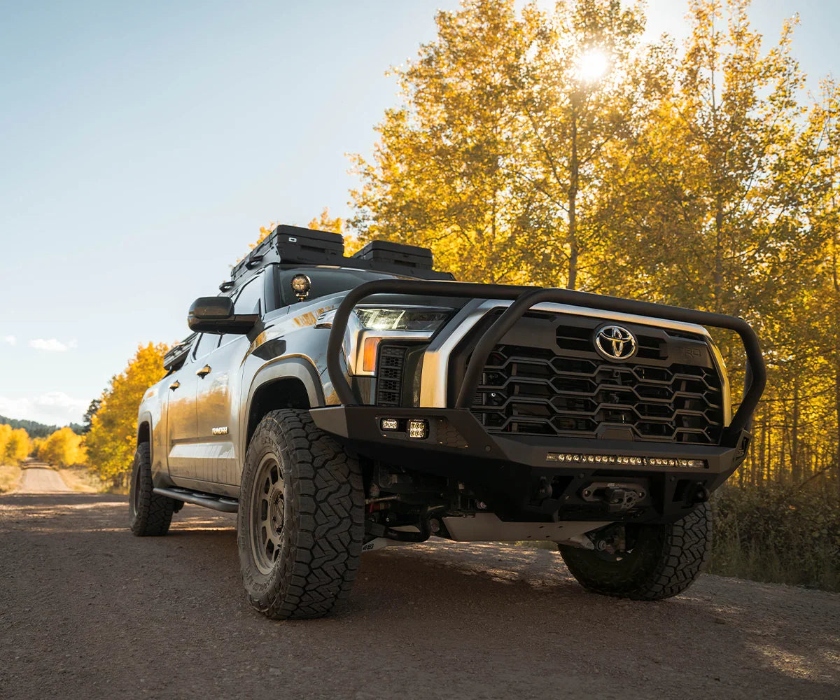 Toyota Tundra with rugged adventure front bumper on dirt road in autumn landscape