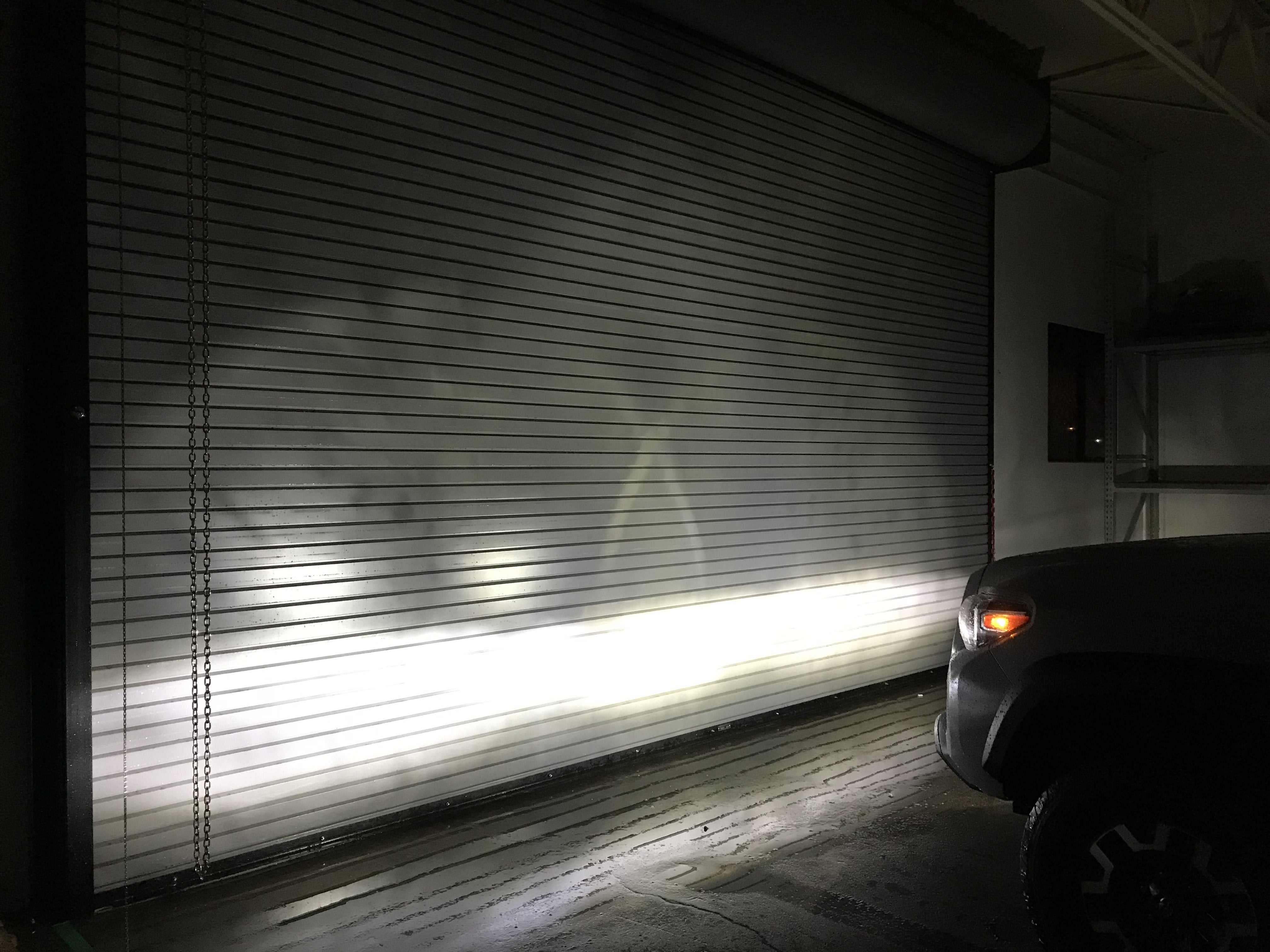 Toyota vehicle fog light beam pattern shining on garage door in dark indoor setting