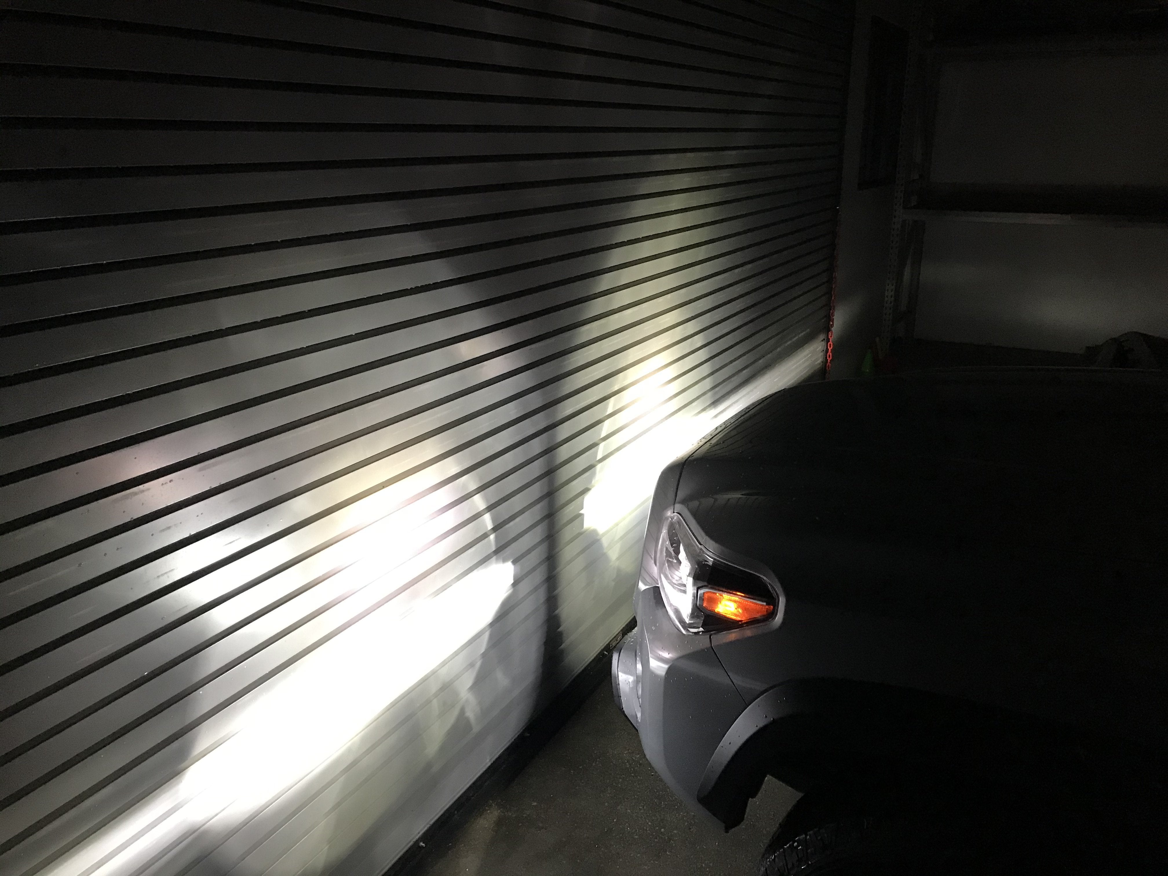 Toyota vehicle fog lights projecting tri-color beams onto garage door at night