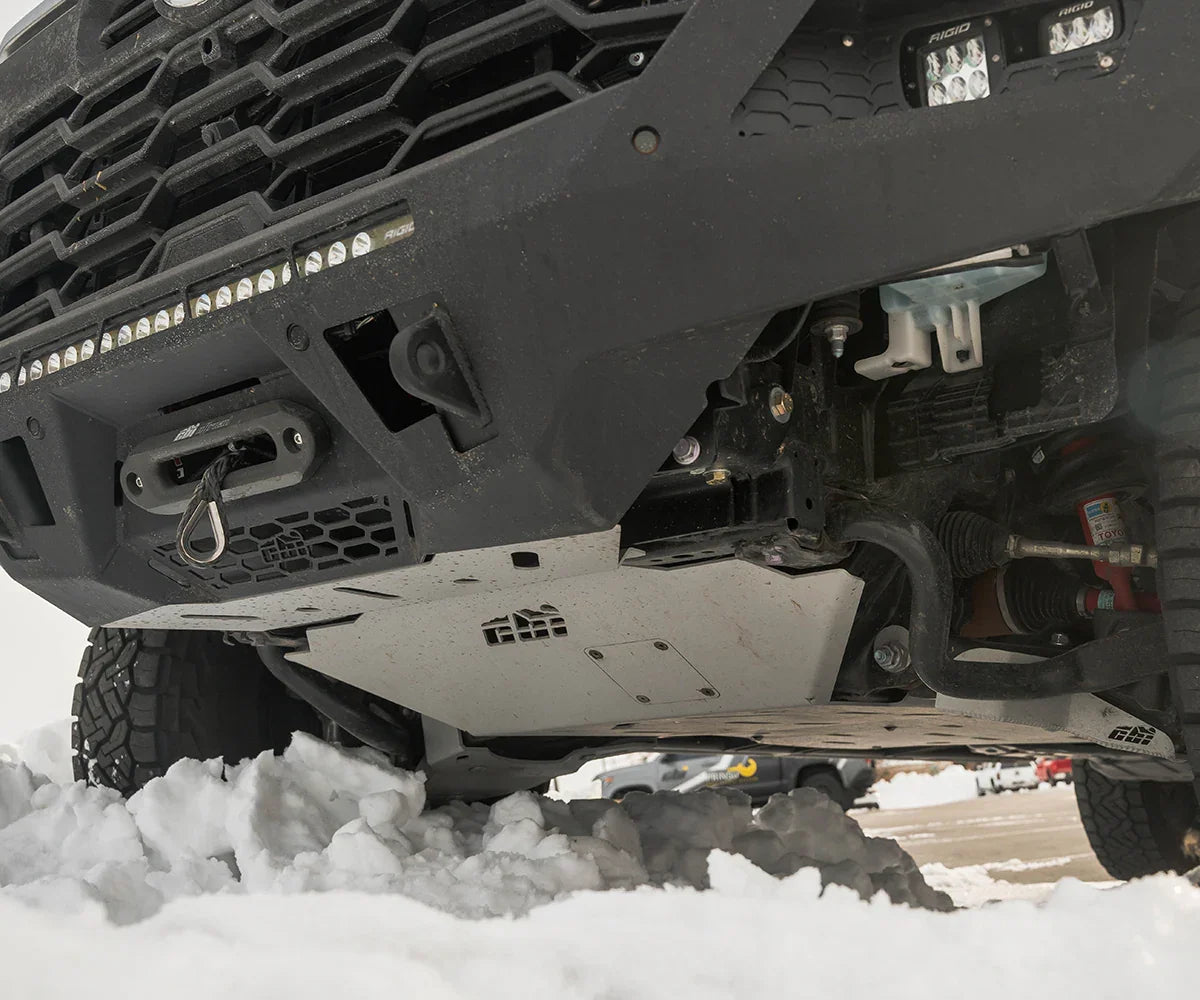 Front skid plate and off-road bumper on SUV in snowy terrain, showing undercarriage protection.