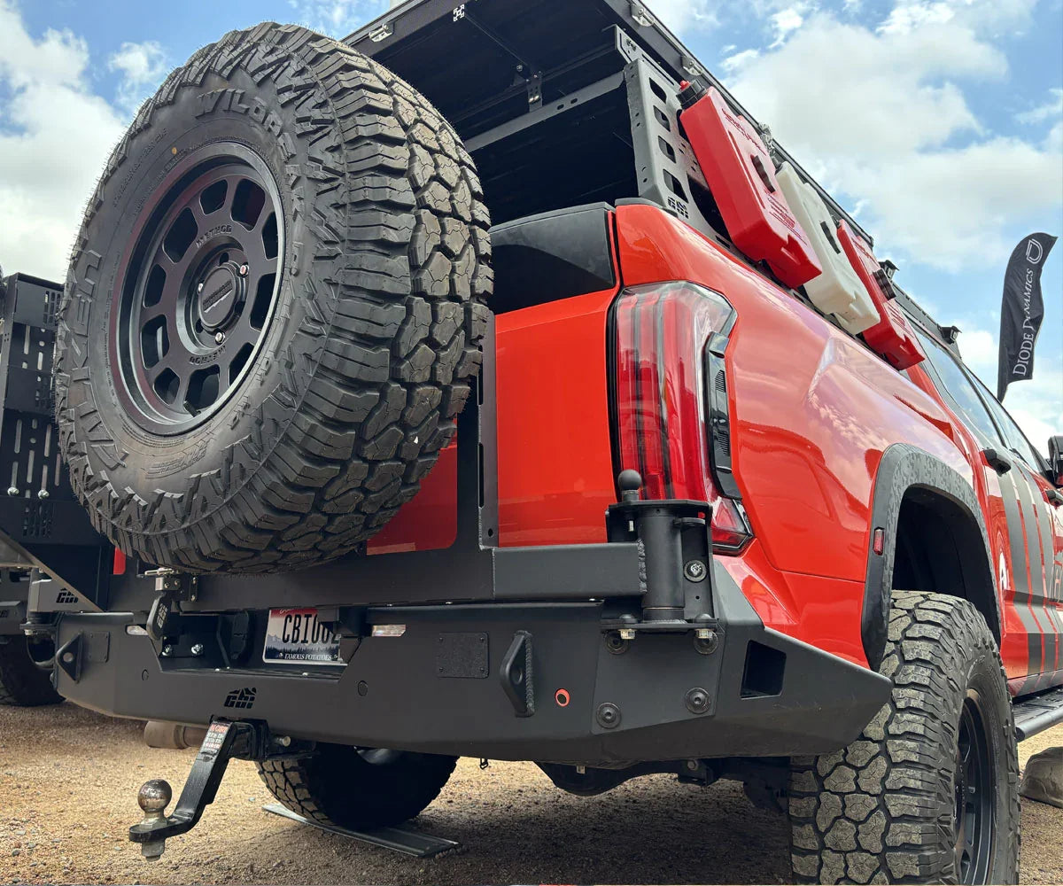 Toyota Tundra with off-road rear bumper, spare tire, fuel can holders, and expedition gear