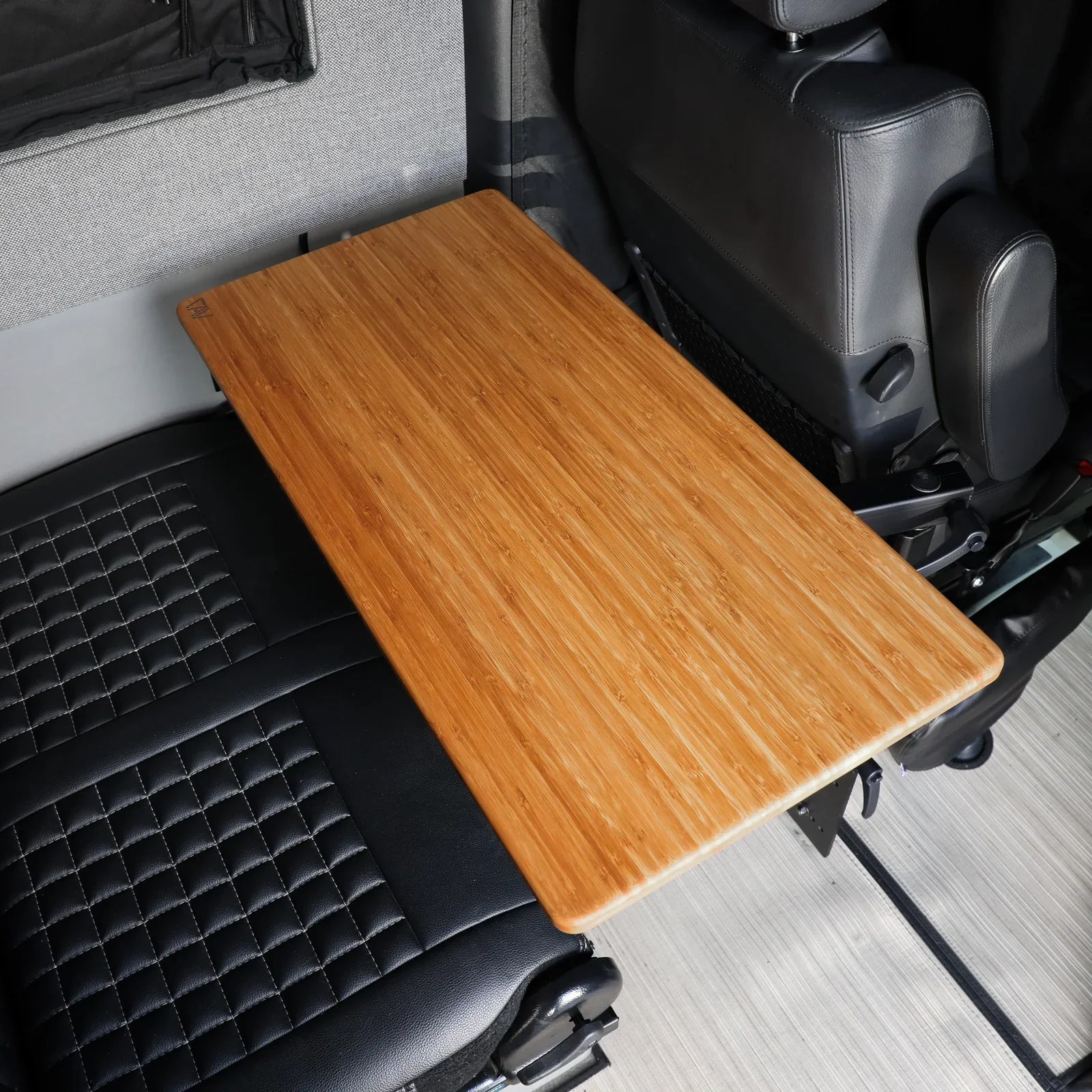 Universal bamboo folding table mounted between black car seats for overlanding vehicles