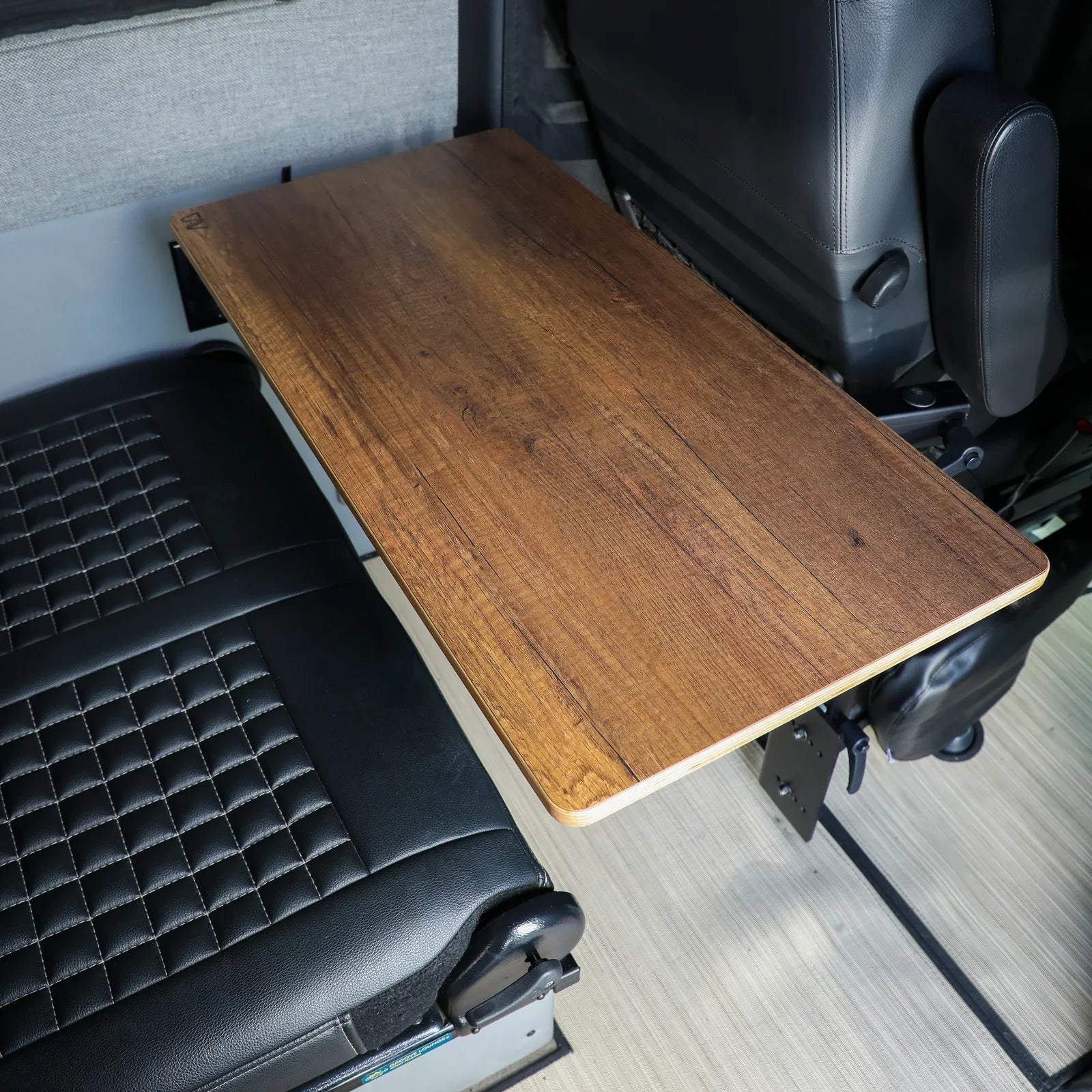 Wooden fold-out table mounted in a vehicle interior with black leather seats