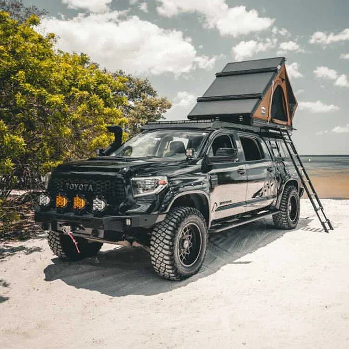 Toyota Tundra overland truck with rooftop tent and off-road accessories on a sandy beach