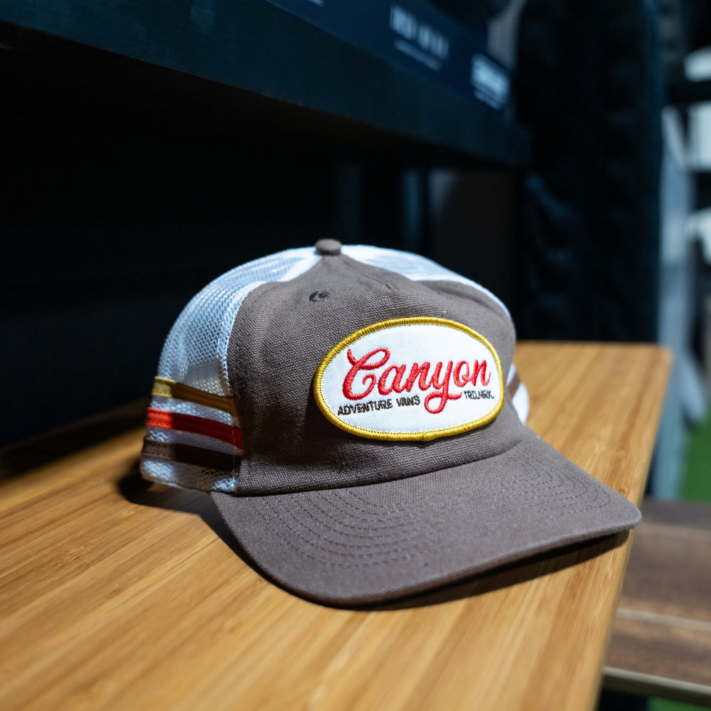 Brown mesh trucker hat with 'Canyon Adventure Vans' patch, outdoor camping accessory