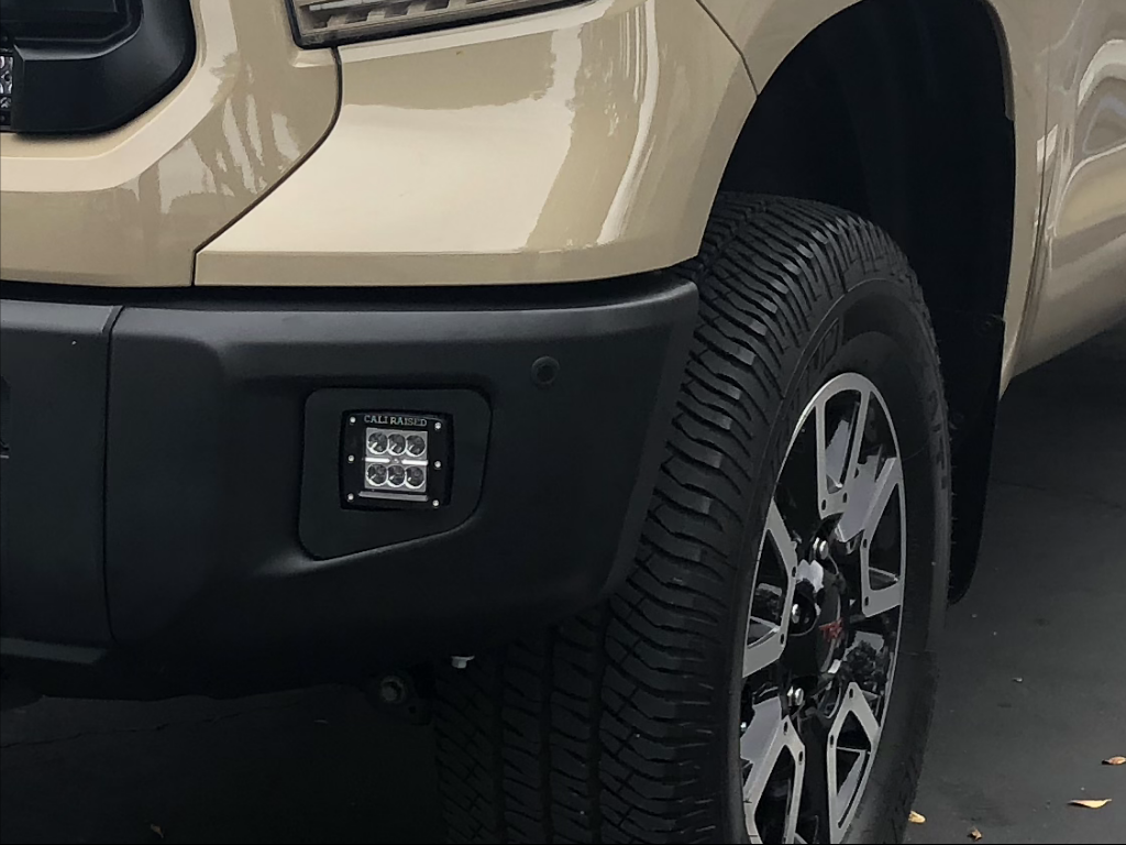 Off-road vehicle front bumper with Cali Raised LED fog light, custom all-terrain tire and rim
