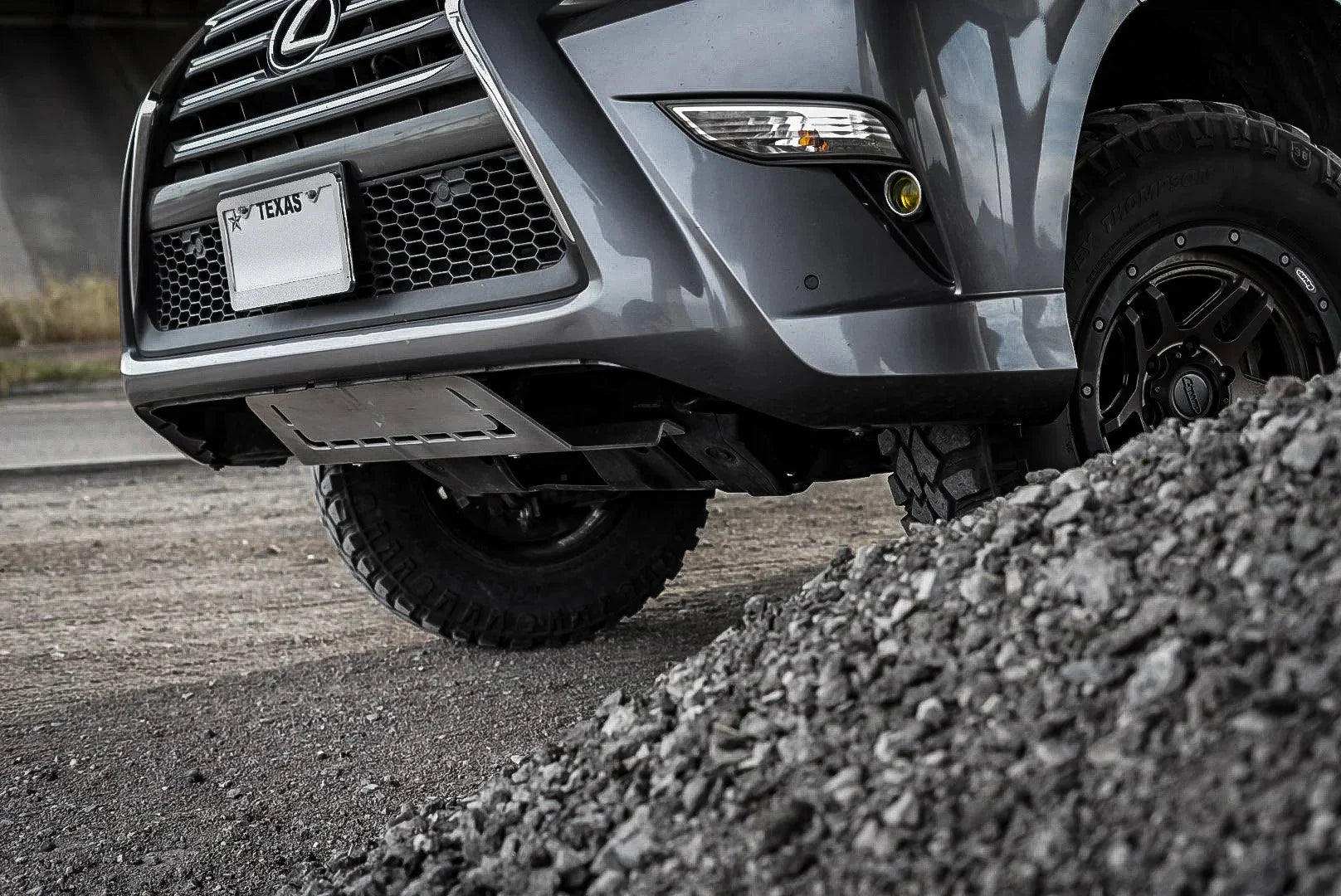 Off-road Lexus SUV with skid plate and rugged tires climbing over gravel