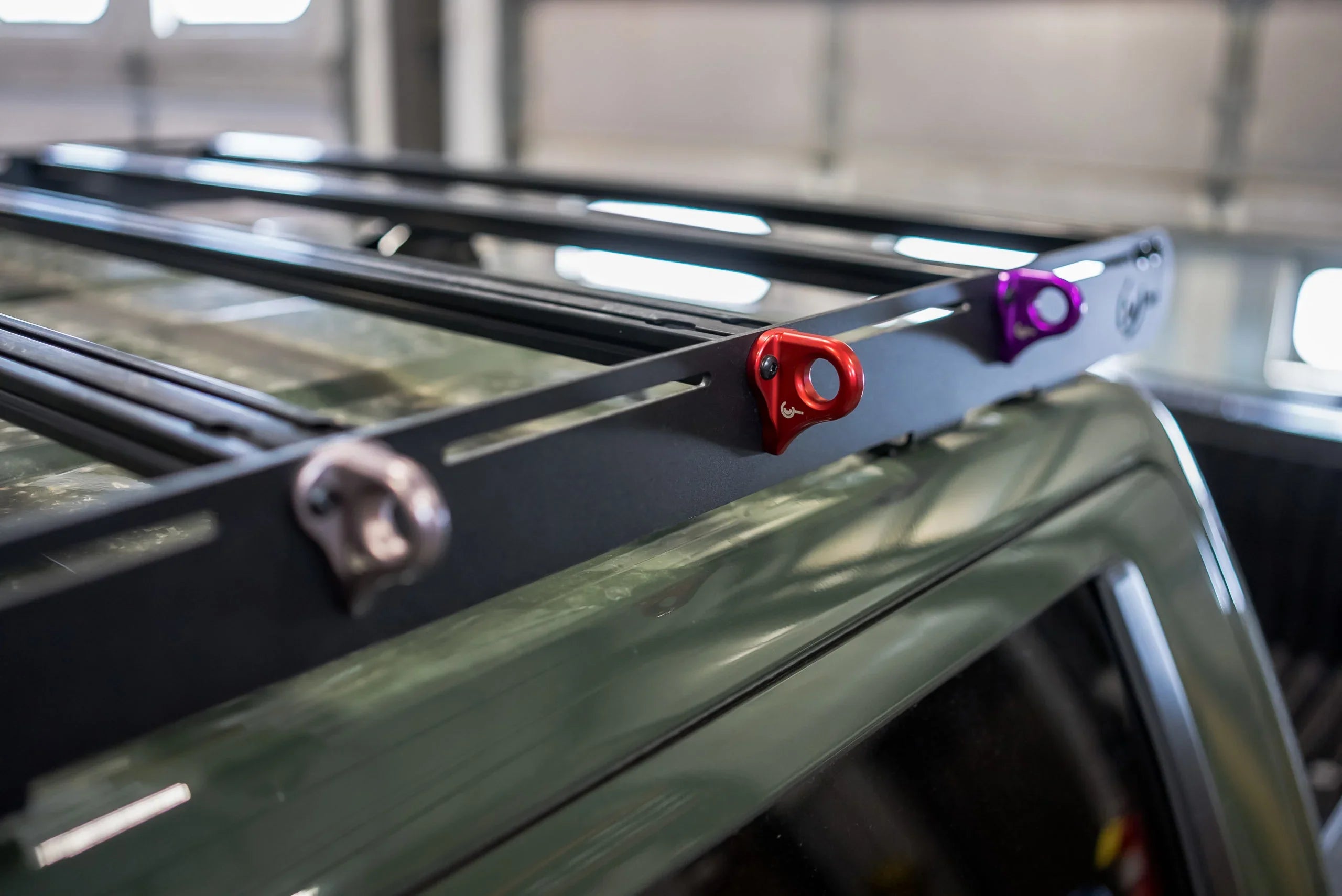 Colorful utility hook mounts on a vehicle roof rack for overlanding and camping gear
