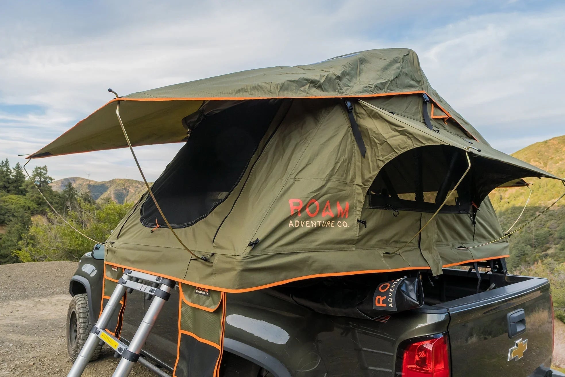 Overland rooftop tent mounted on a truck in a scenic outdoor setting