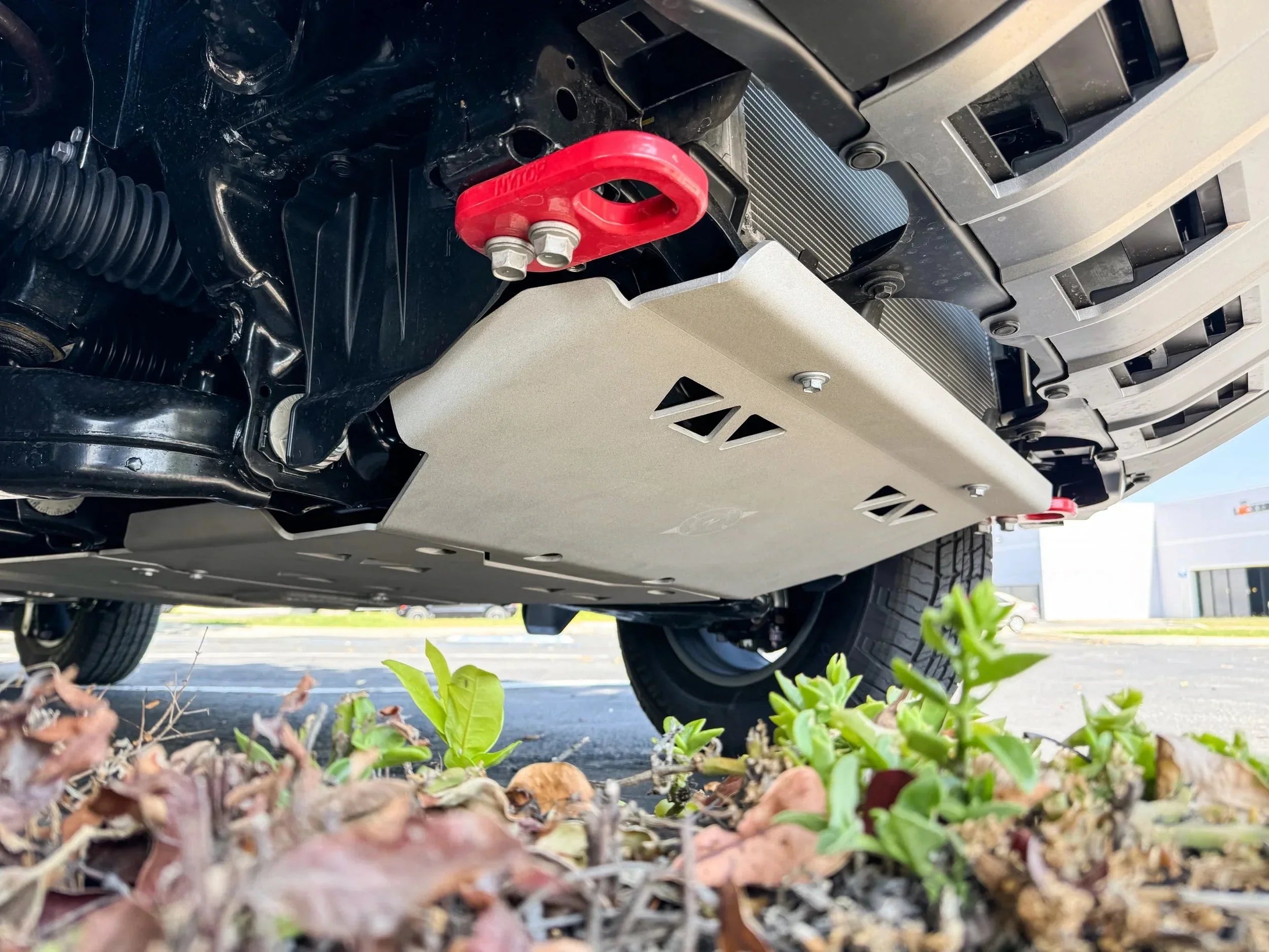 Heavy-duty skid plate and red recovery point mounted under an off-road vehicle