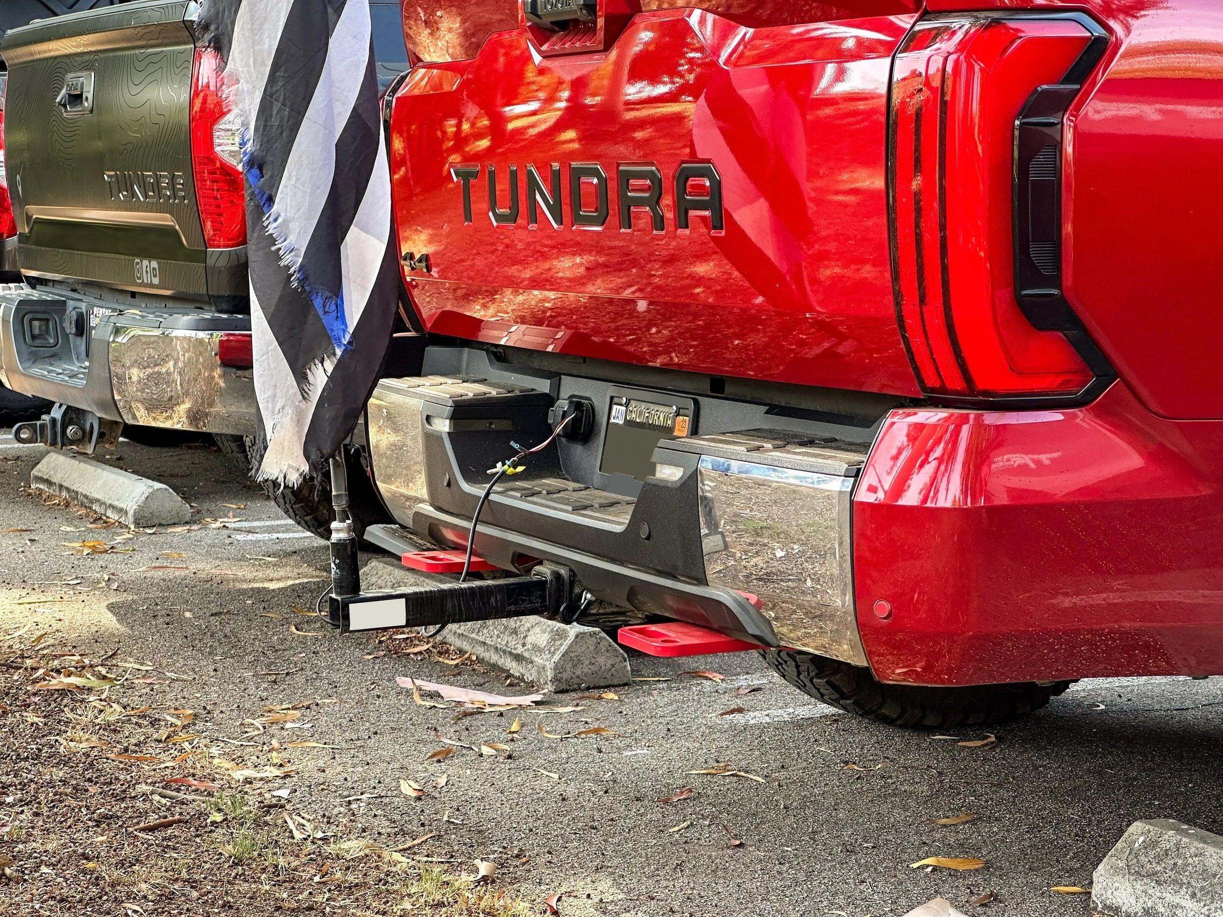 Toyota Tundra trucks with towing accessories and hitch flag mount in parking lot