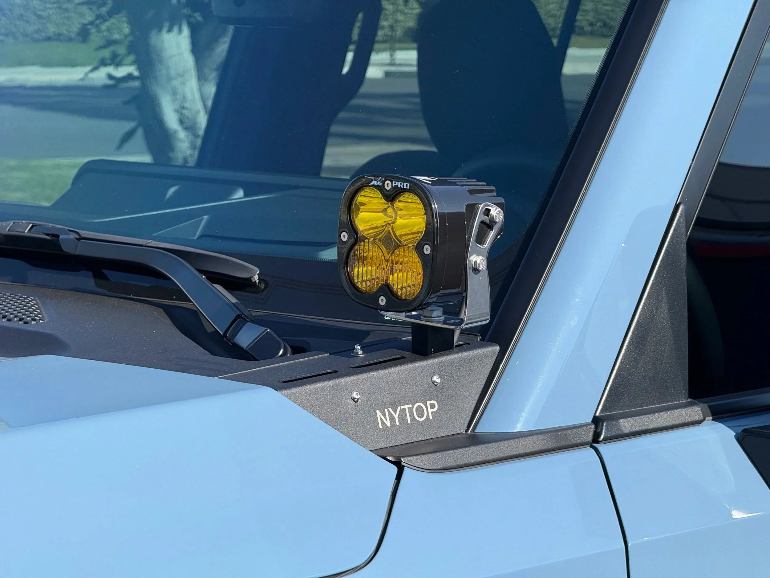 Yellow off-road LED ditch light mounted on vehicle windshield bracket, overland accessory